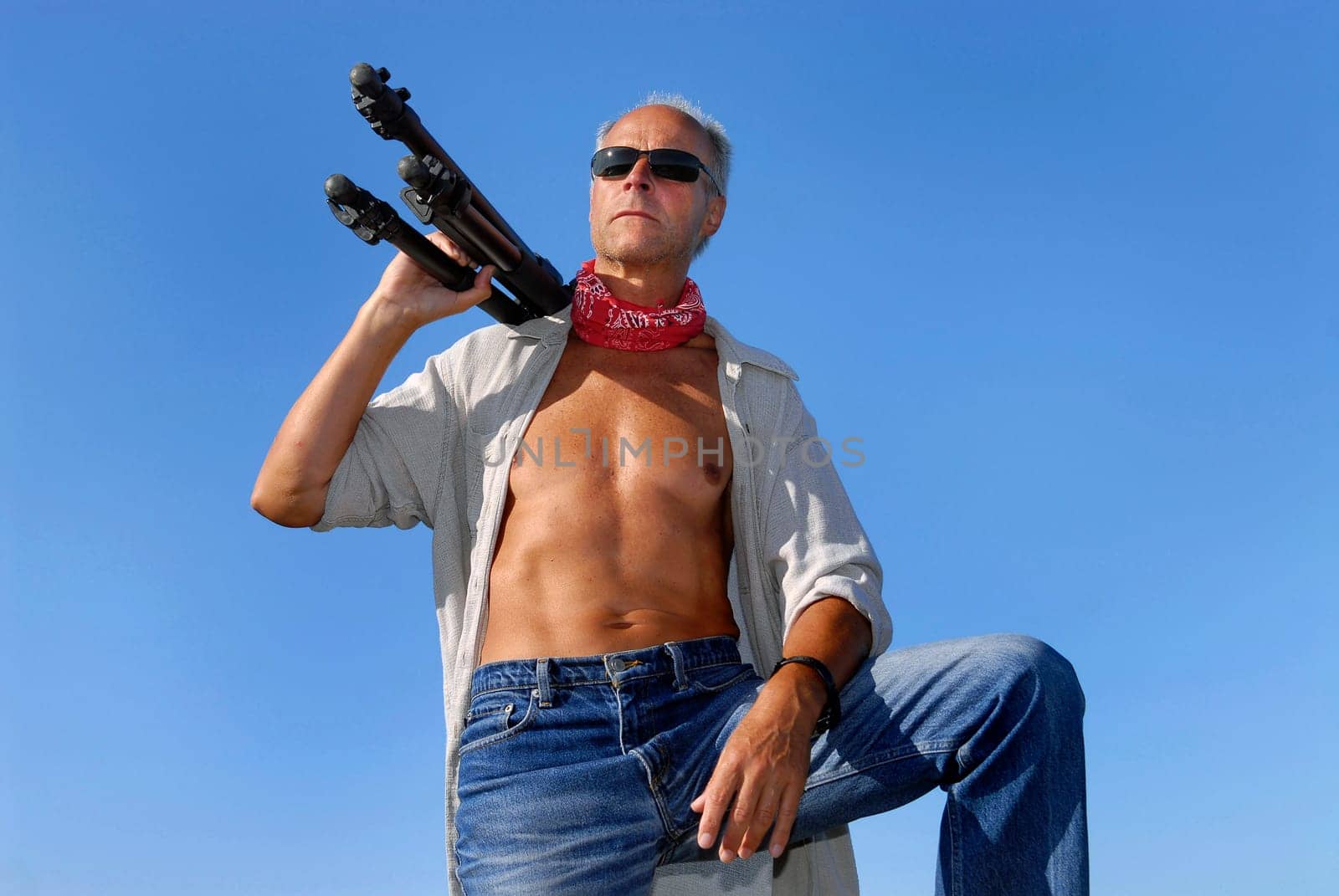 Handsome mature man adventurer, posing with a tripod outdoors