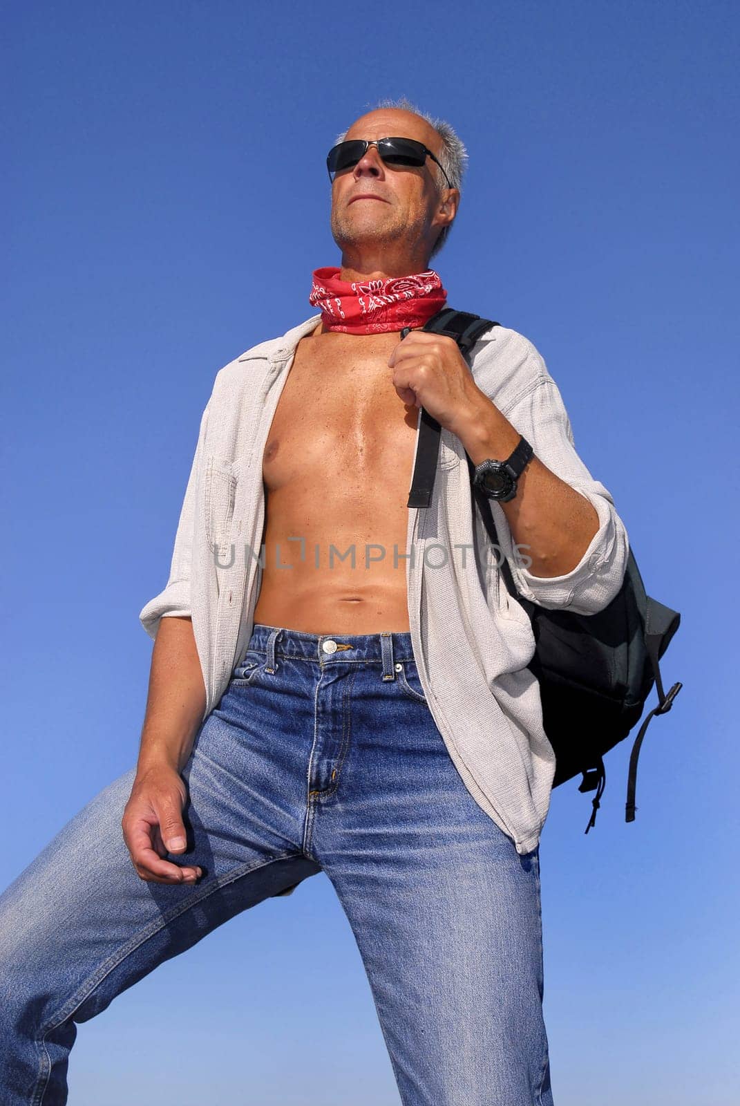 Handsome mature man adventurer posing with a backpack outdoors