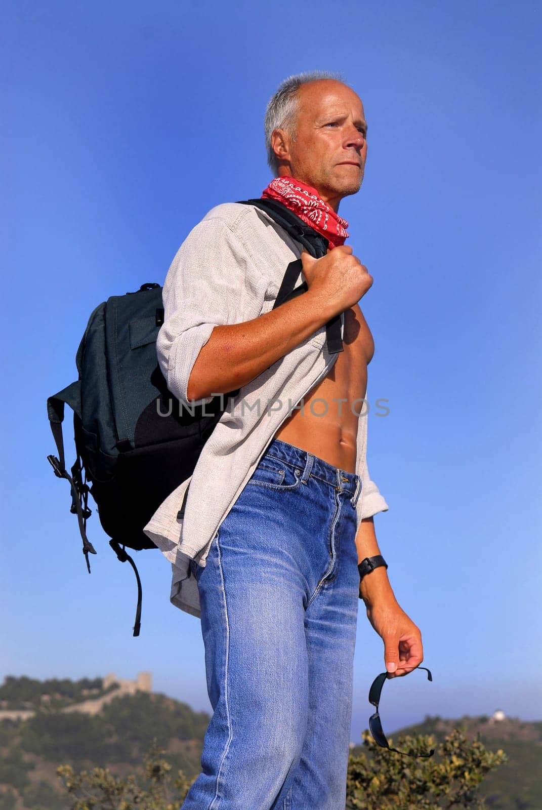 Handsome mature man adventurer posing outdoors with a backpack
