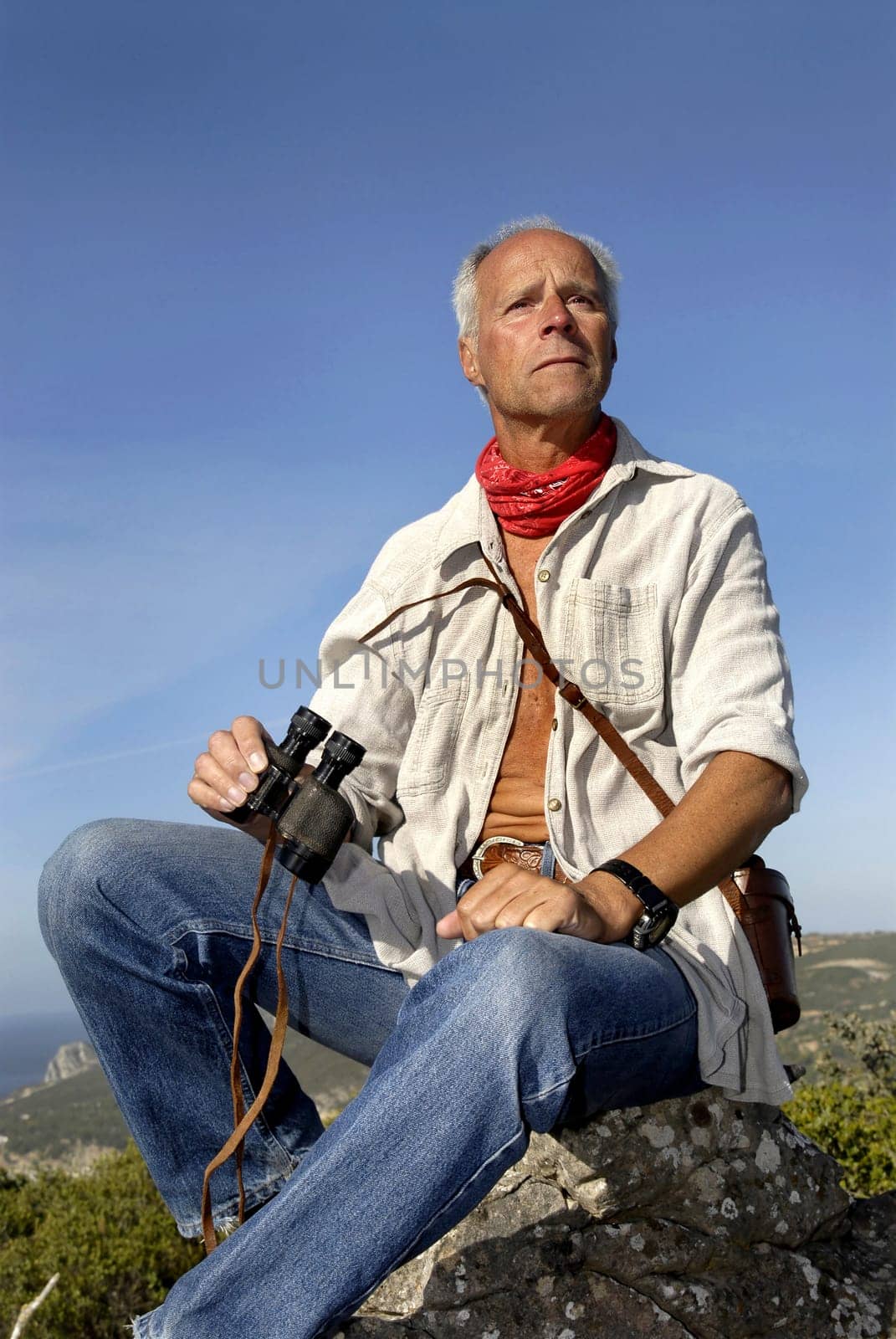 Mature man explorer posing outdoors with is binoculars