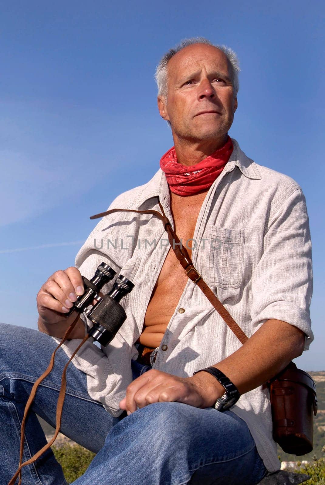 Explorer posing outdoors with is binoculars looking for adventure