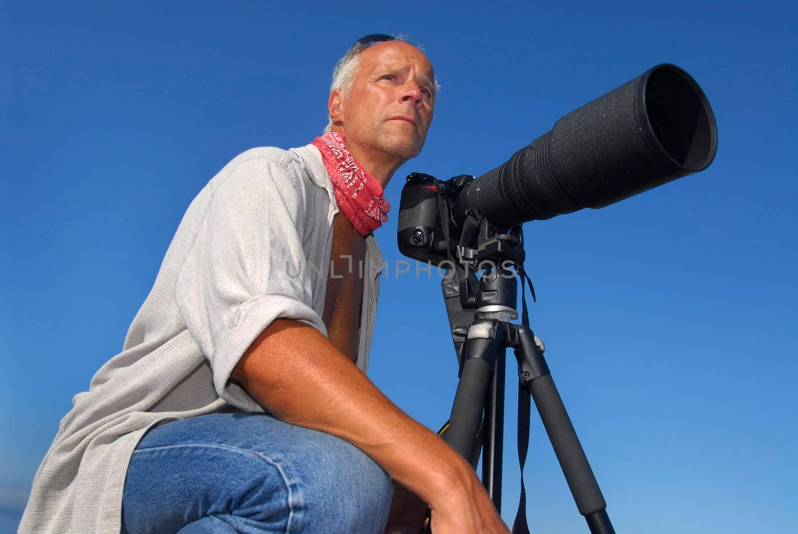 Handsome mature man adventurer posing with a big camera outdoors