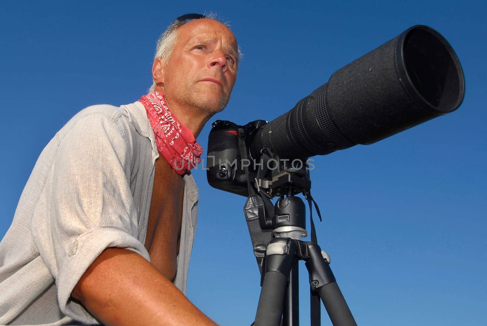 Handsome mature man adventurer posing with a big camera outdoors