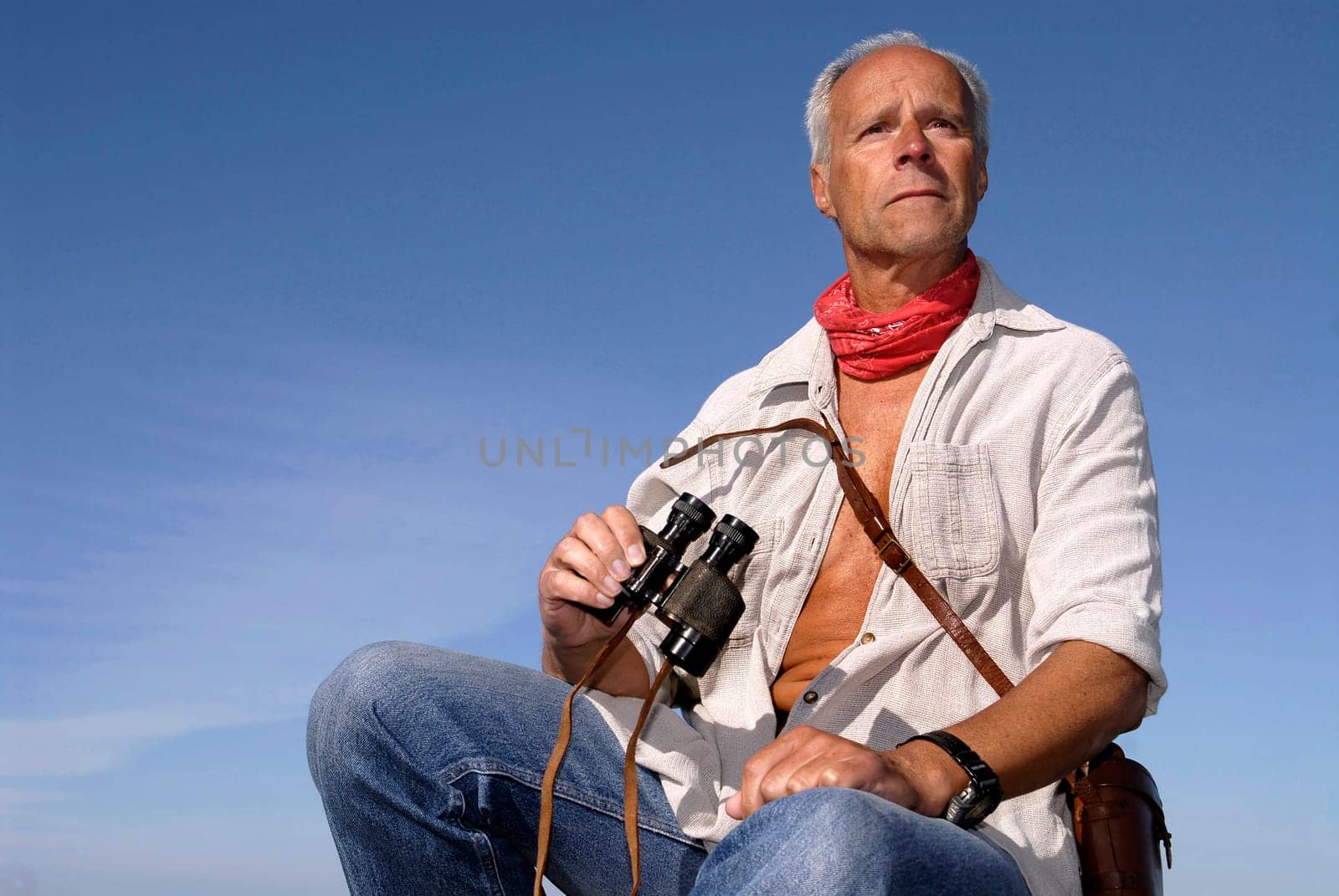 Explorer posing outdoors with is binoculars looking for adventure