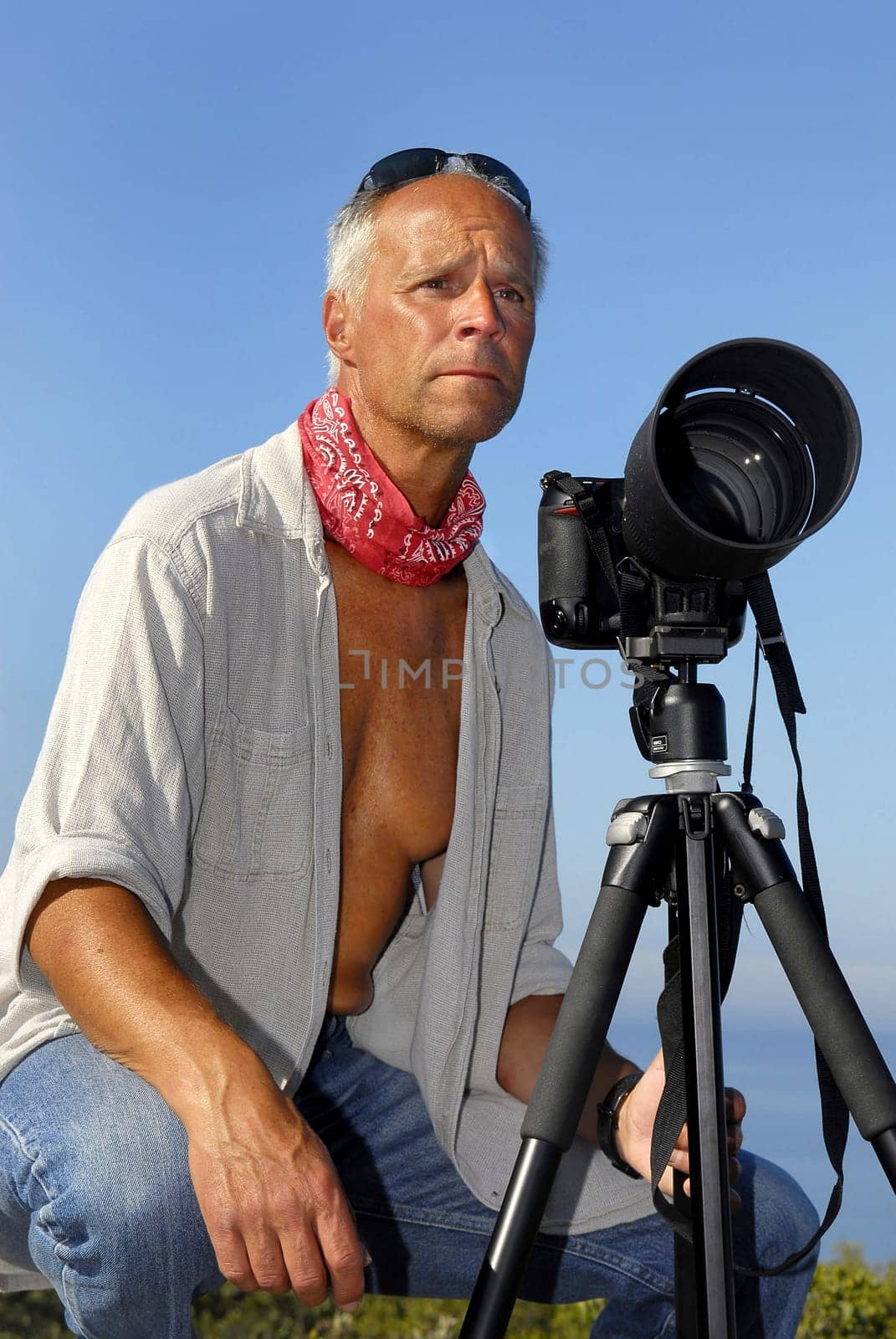 Handsome mature man posing with a big camera outdoors