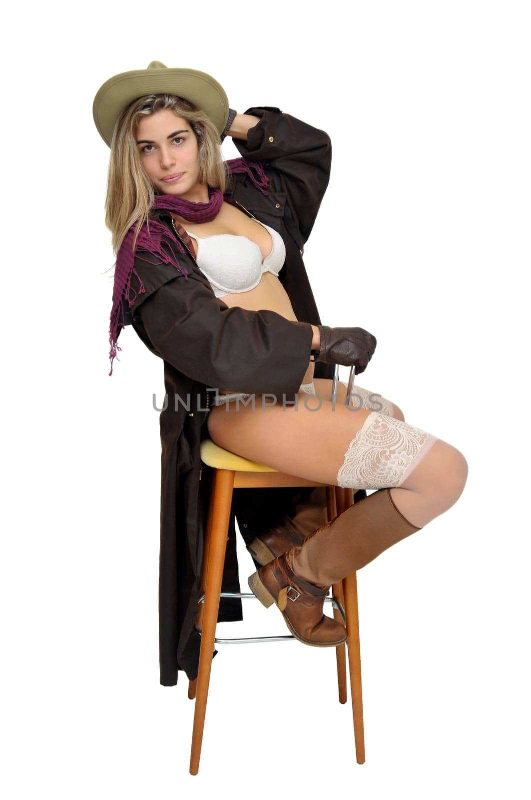 Sexy girl in cowboy outfit in a chair isolated in white