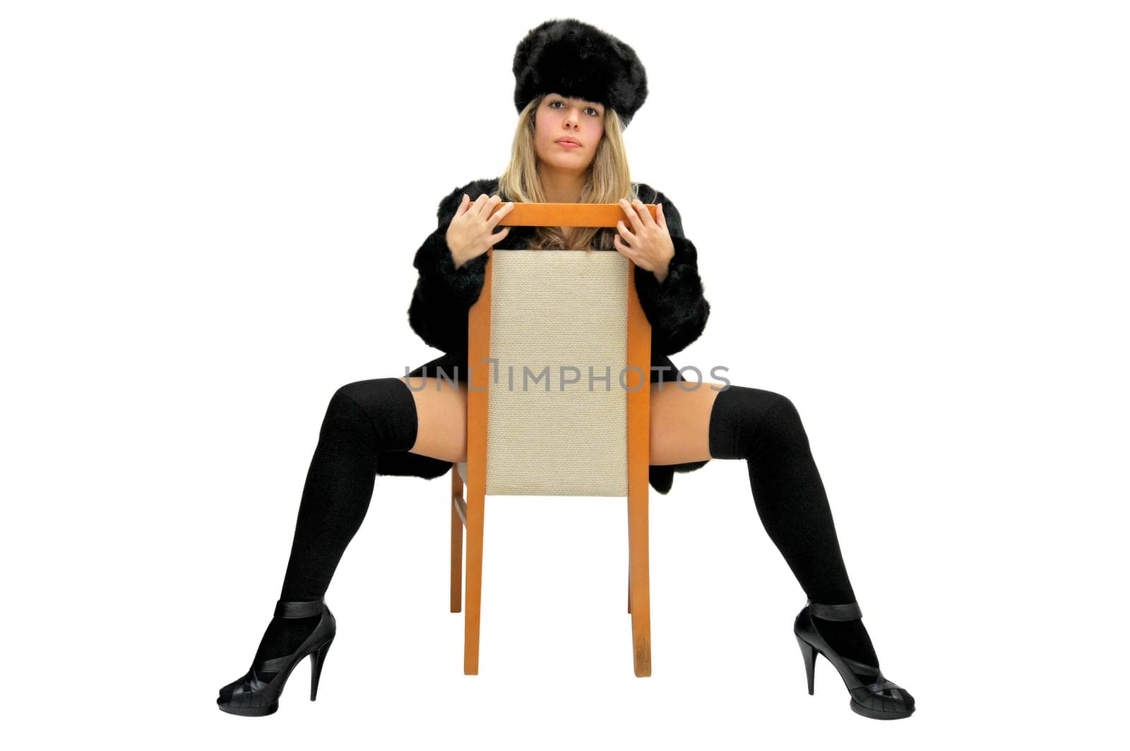 Sexy girl in furs and black lingerie in a chair isolated in white