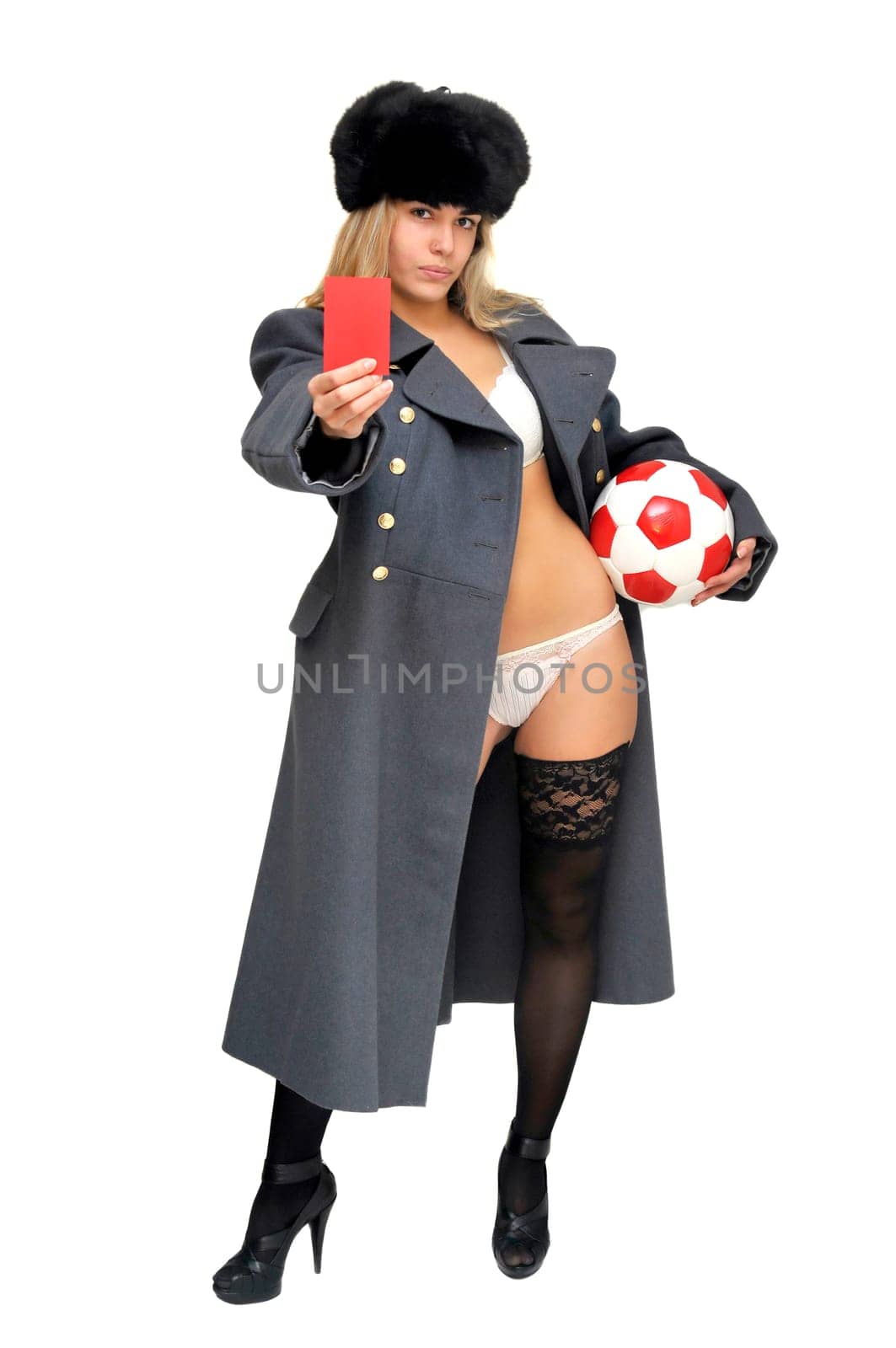 Sexy girl in russian army greatcoat holding a soccer ball and a red card isolated in white