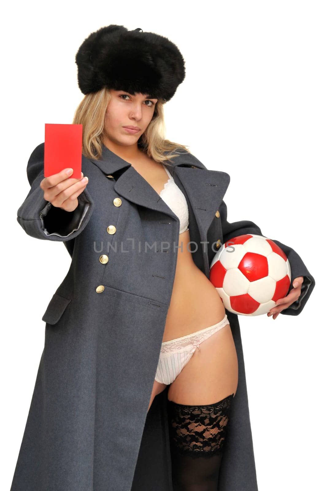 Sexy girl in russian army greatcoat holding a soccer ball and a red card isolated in white