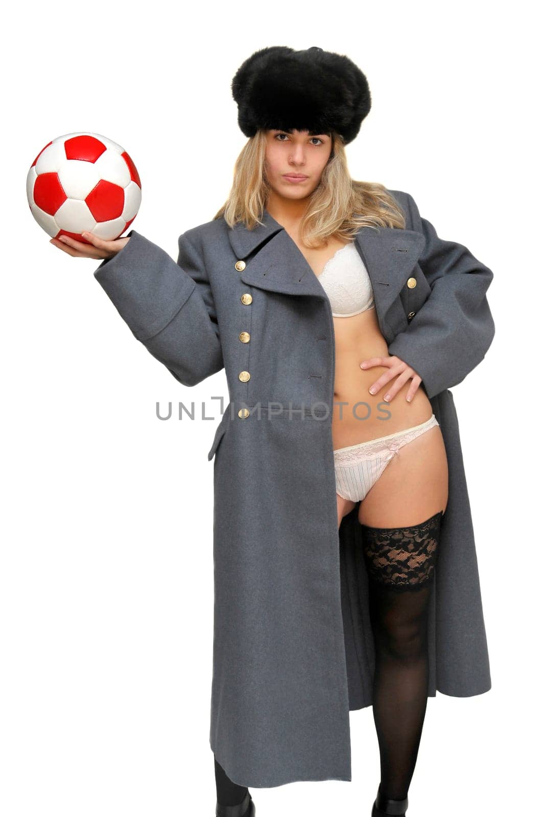 Sexy girl in russian army greatcoat and lingerie holding a soccer ball isolated in white