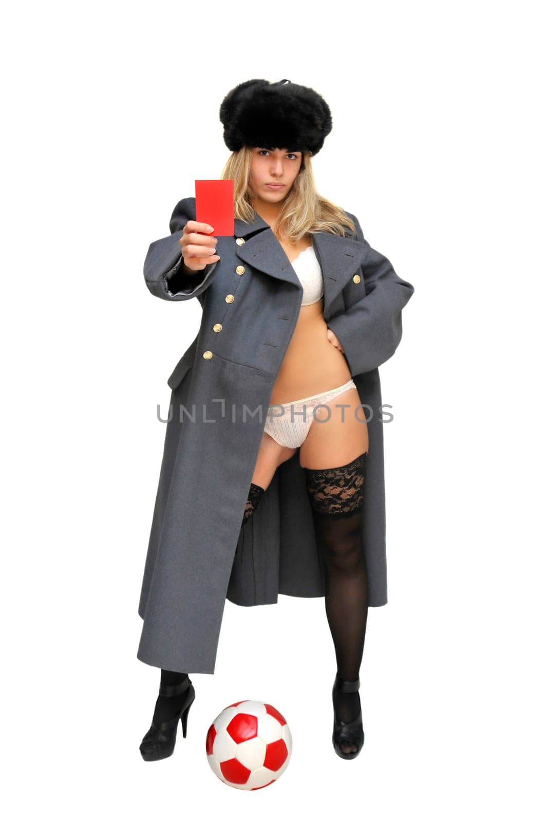 Sexy girl in russian army greatcoat holding a soccer ball and a red card isolated in white