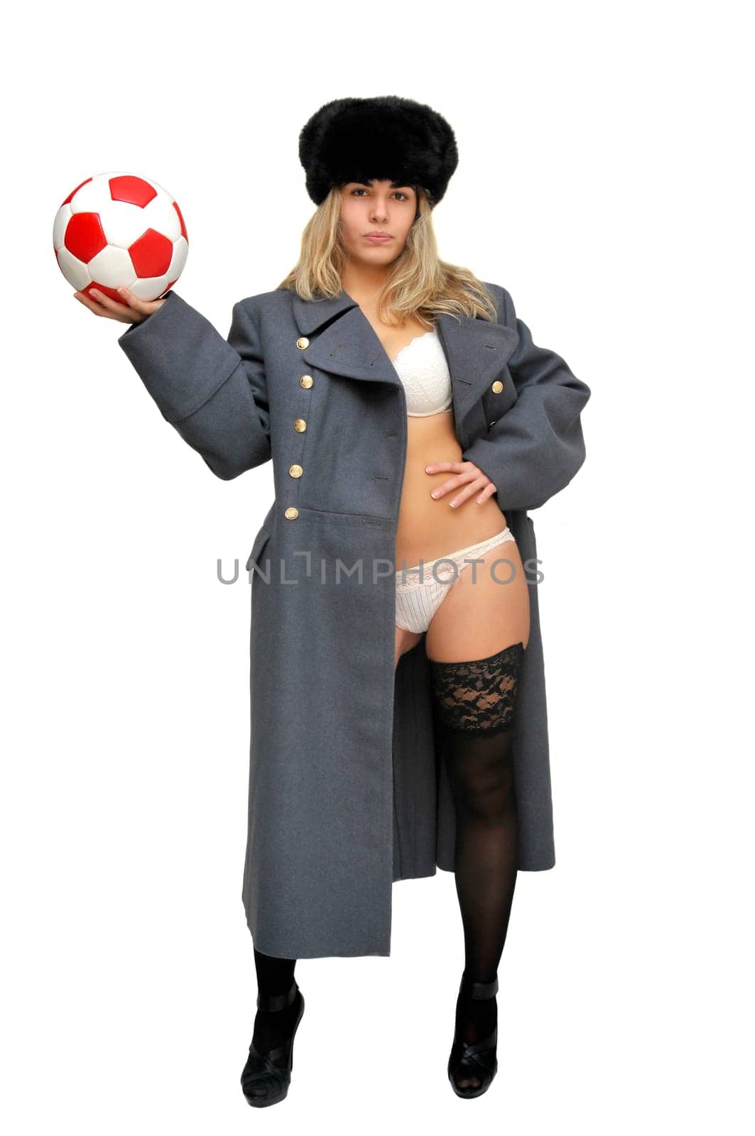 Sexy girl in russian army greatcoat and lingerie holding a soccer ball isolated in white