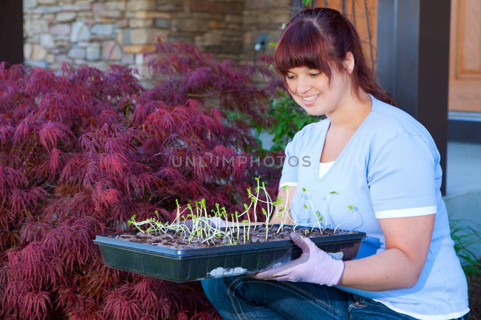 A young woman displays a tray of seedlings for her vegetable garden