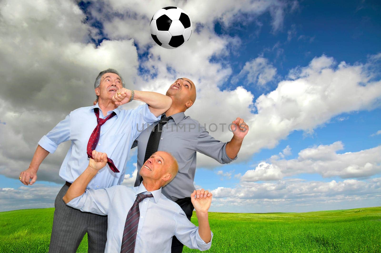 Businessmen playing soccer outdoors
