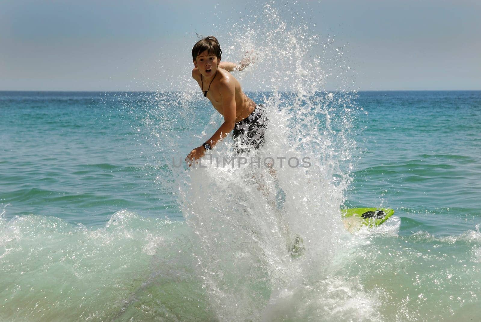 Boy jumping in the air with skimboard in the sea