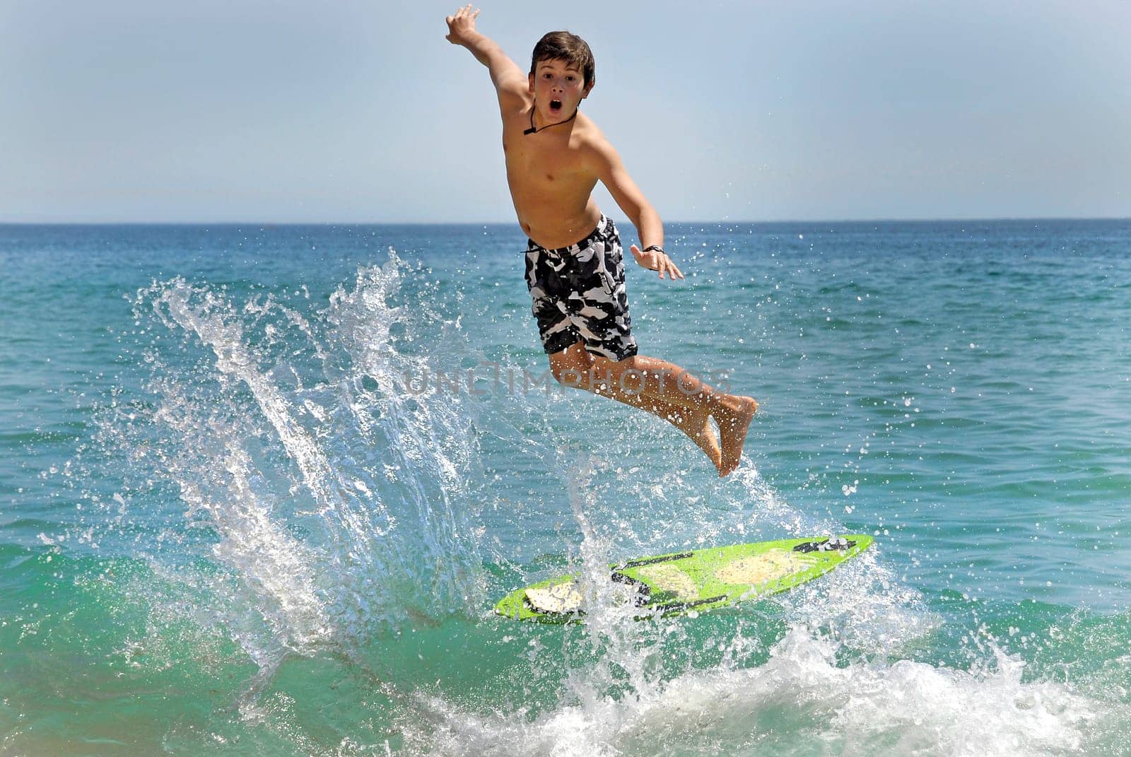 Boy jumping in the air with skimboard in the sea