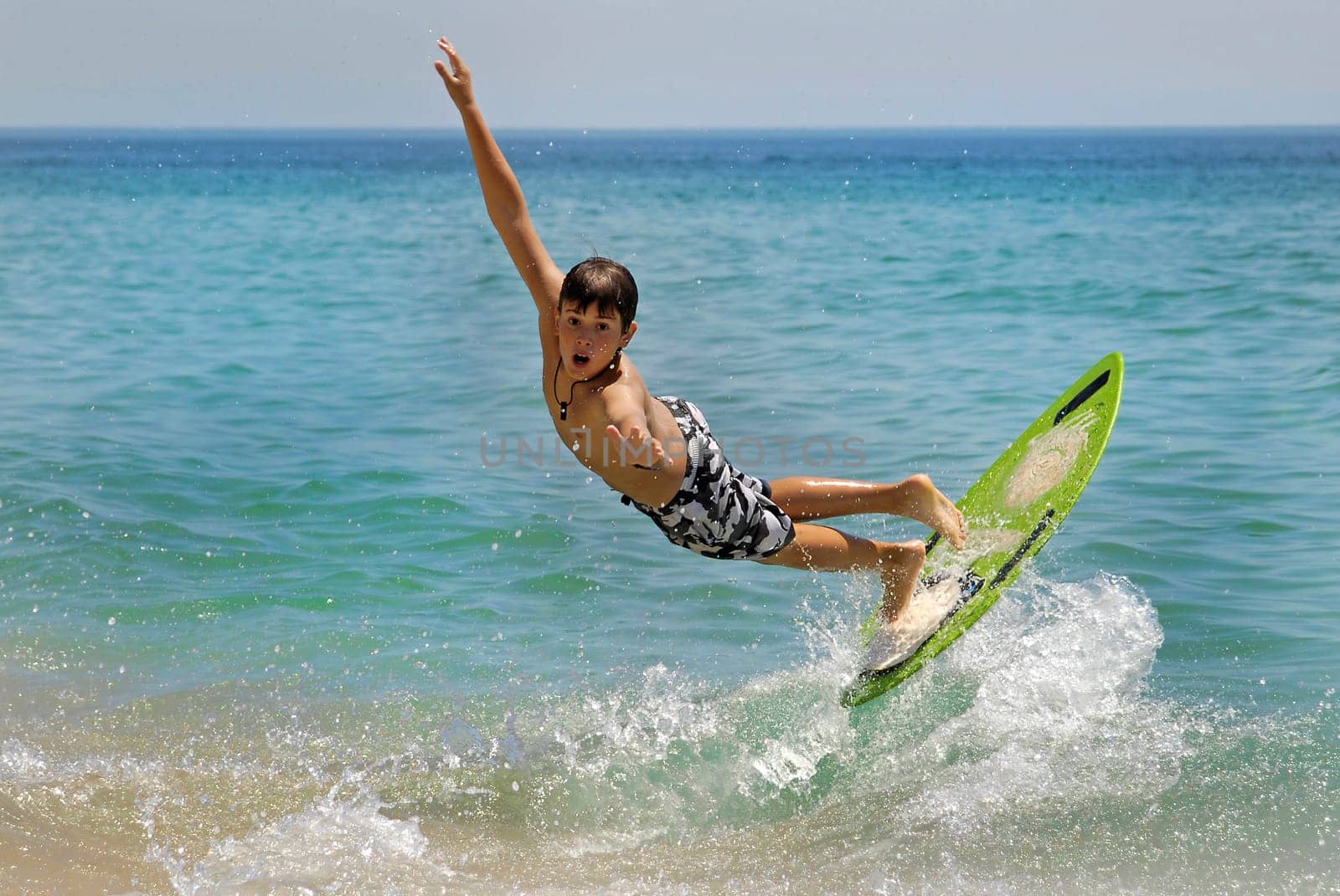 Boy jumping in the air with skimboard in the sea