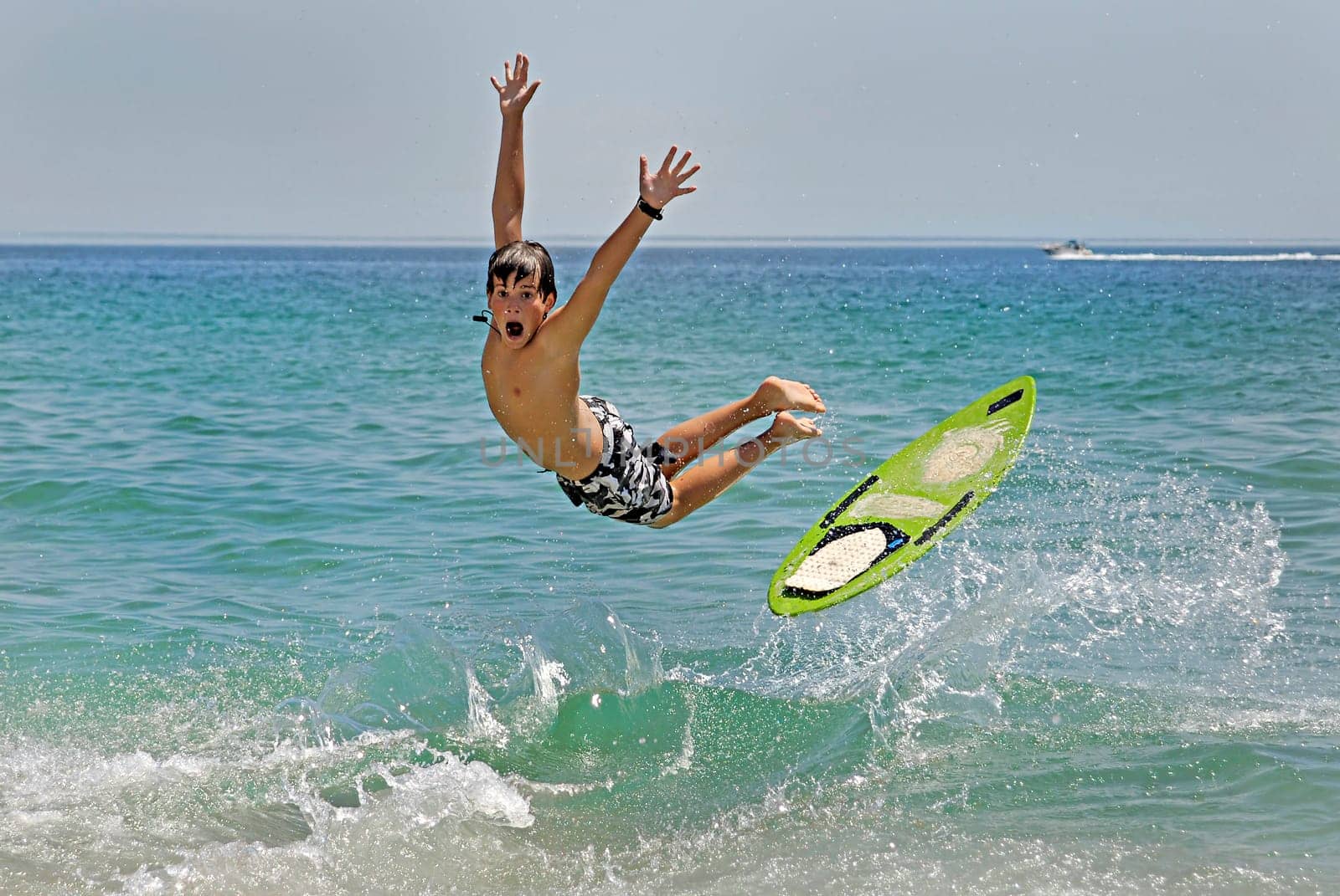 Boy jumping in the air with skimboard in the sea