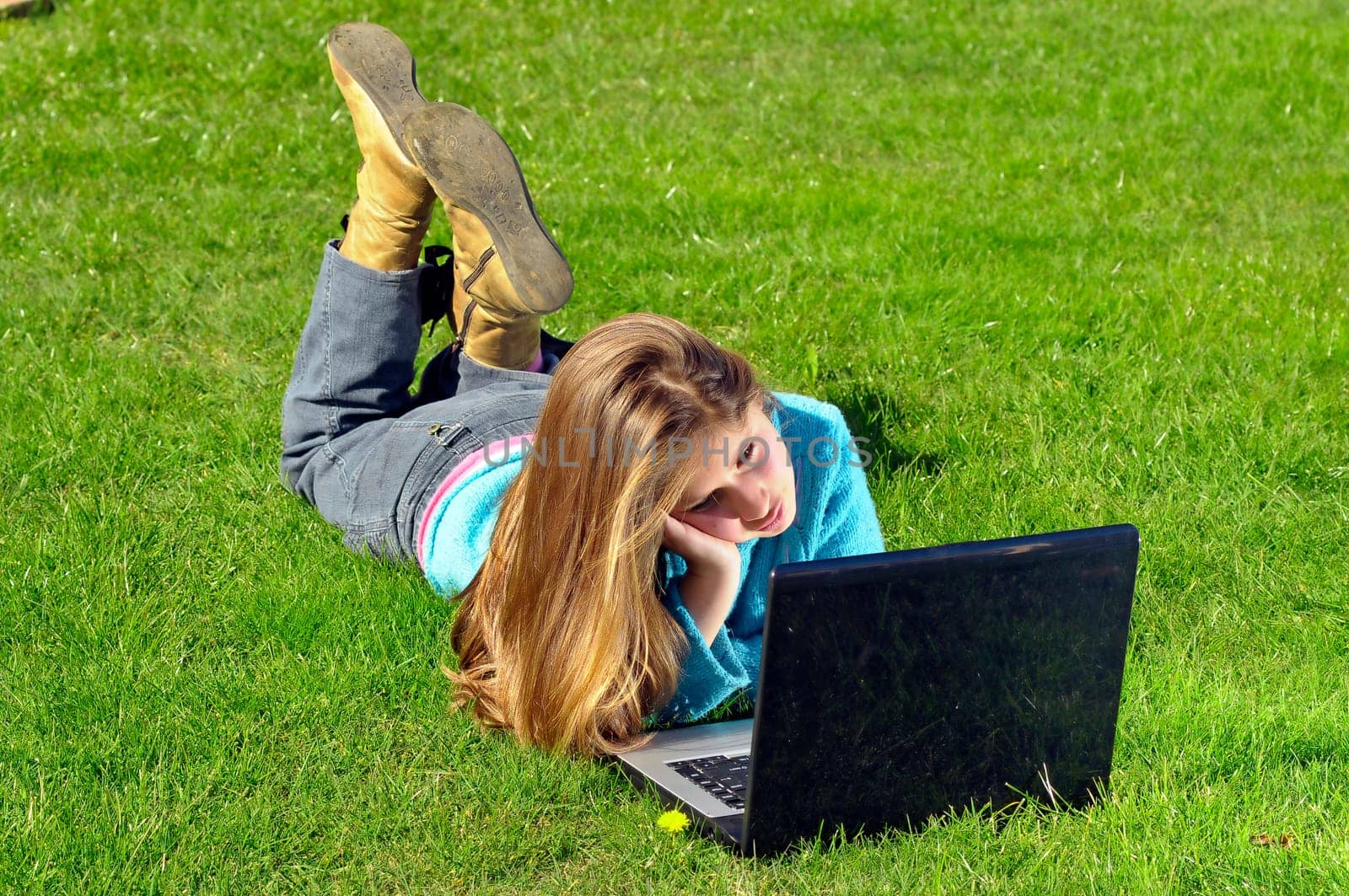 Girl playing with laptop in the grass