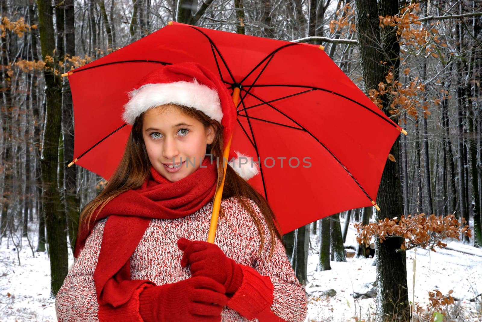 Beautiful young girl with red umbrella in the snow