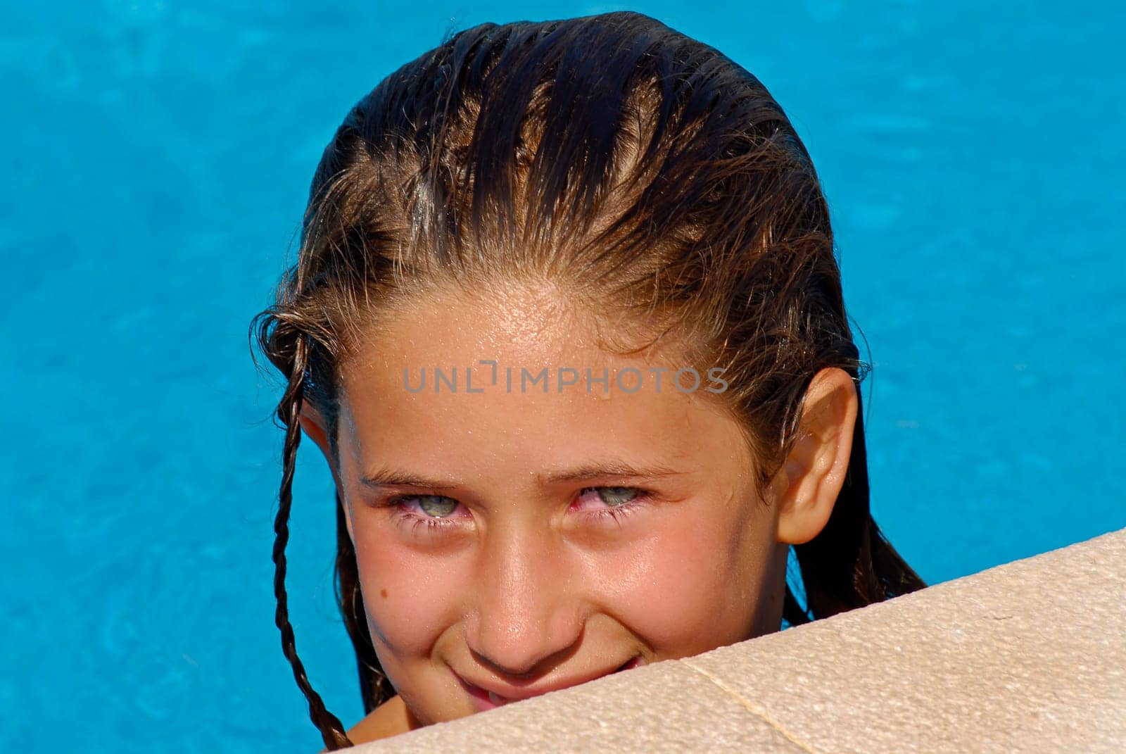 Beautiful young girl with blue eyes posing in the pool