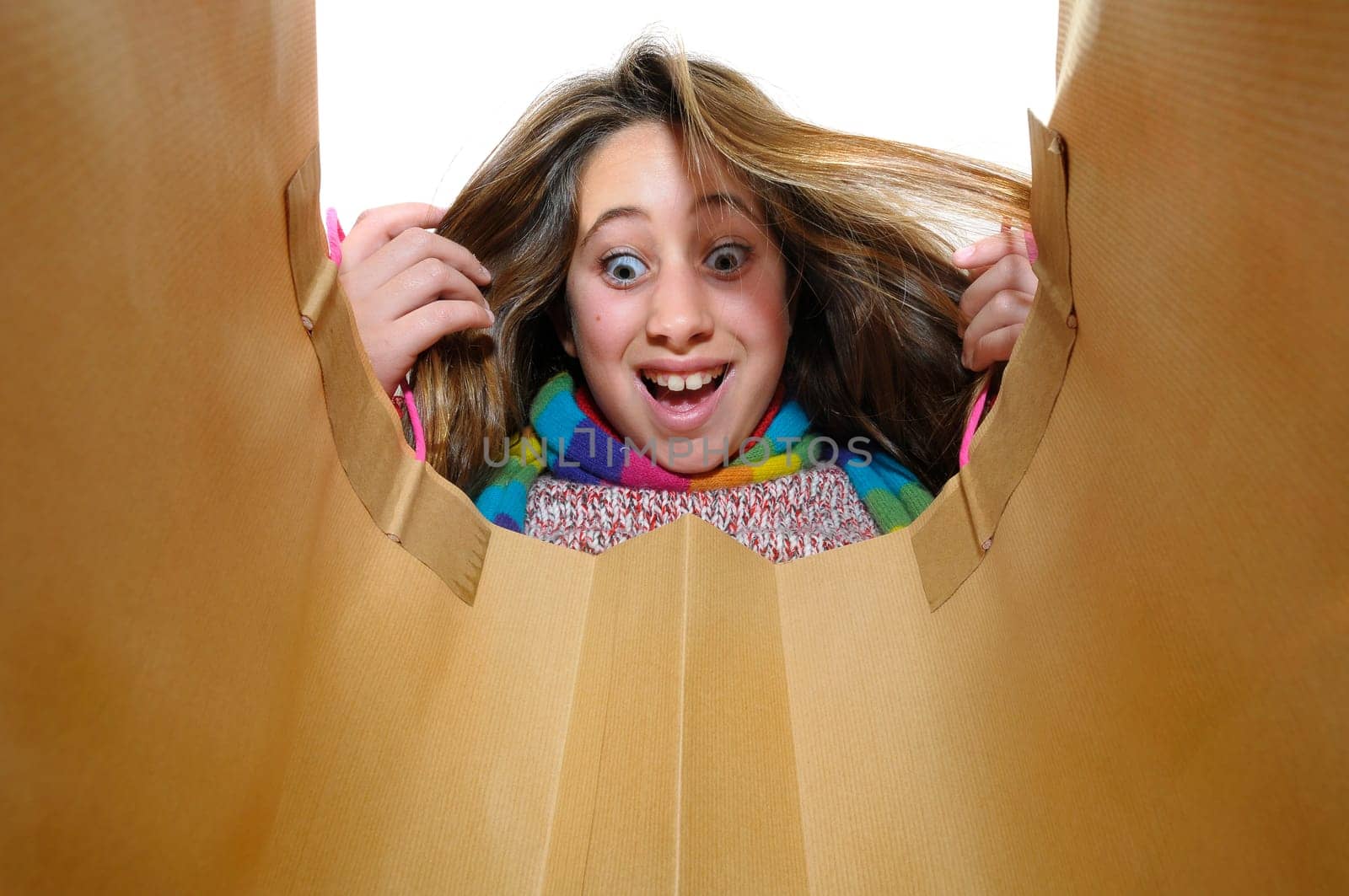 Beautiful young girl looking inside colorful bag isolated in white