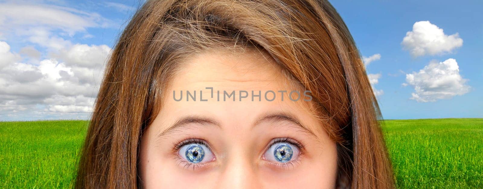 Young girl with planet eyes over a green field with blue cloudy sky