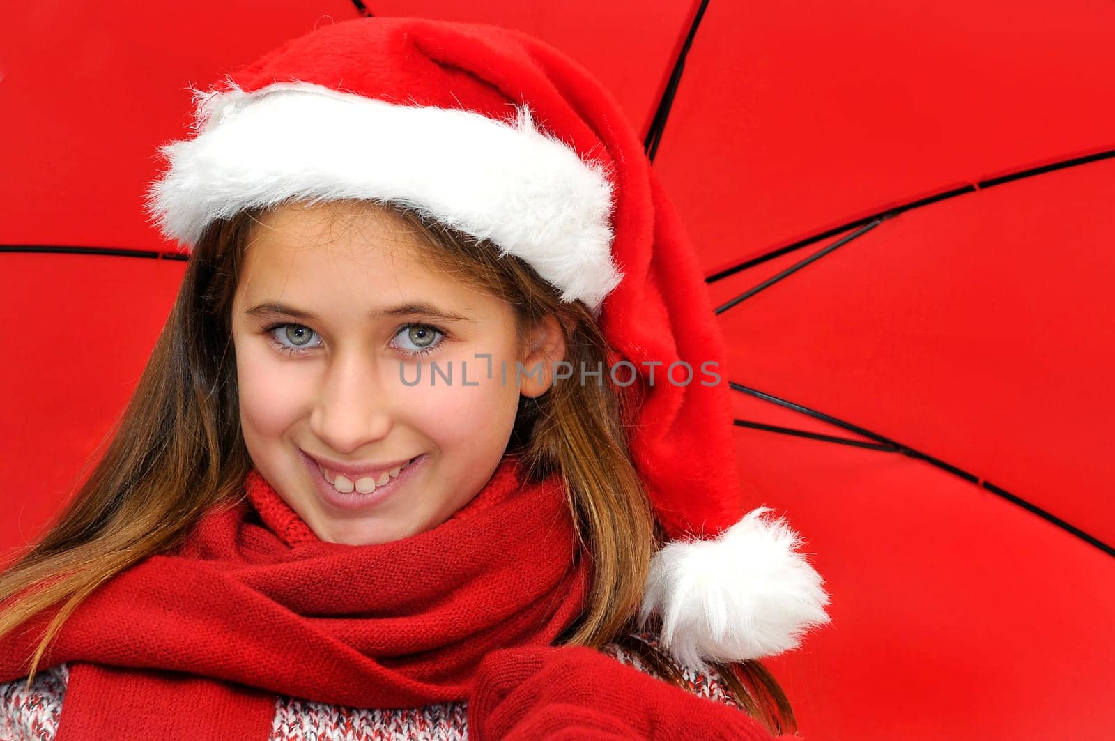 Beautiful young girl with santas hat and red umbrella
