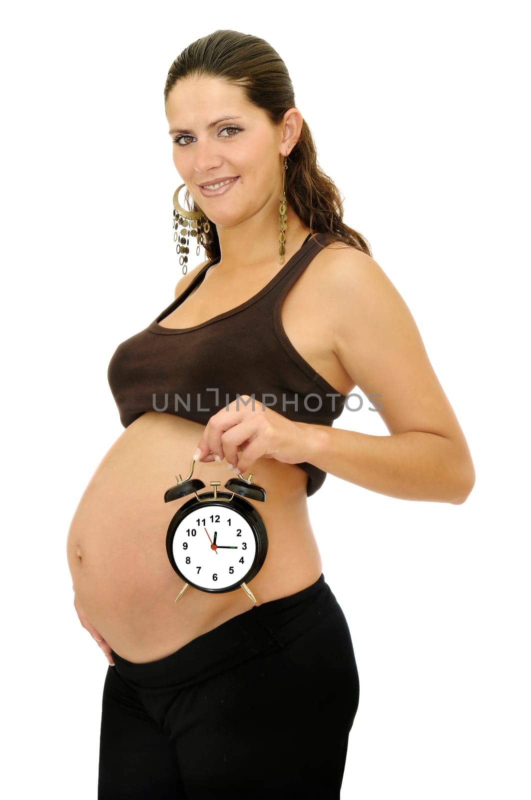 Pregnant woman holding a big alarm clock isolated in white