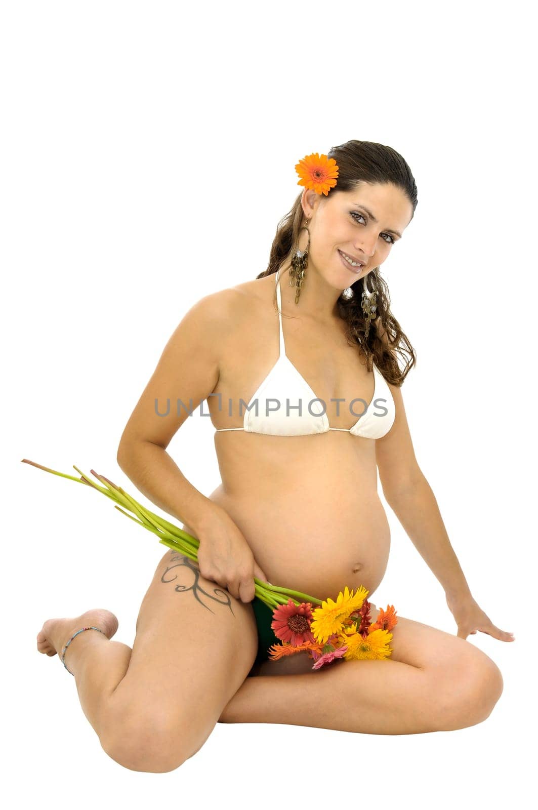 Pregnant woman with tattoo in bikini holding a bunch of flowers isolated in white