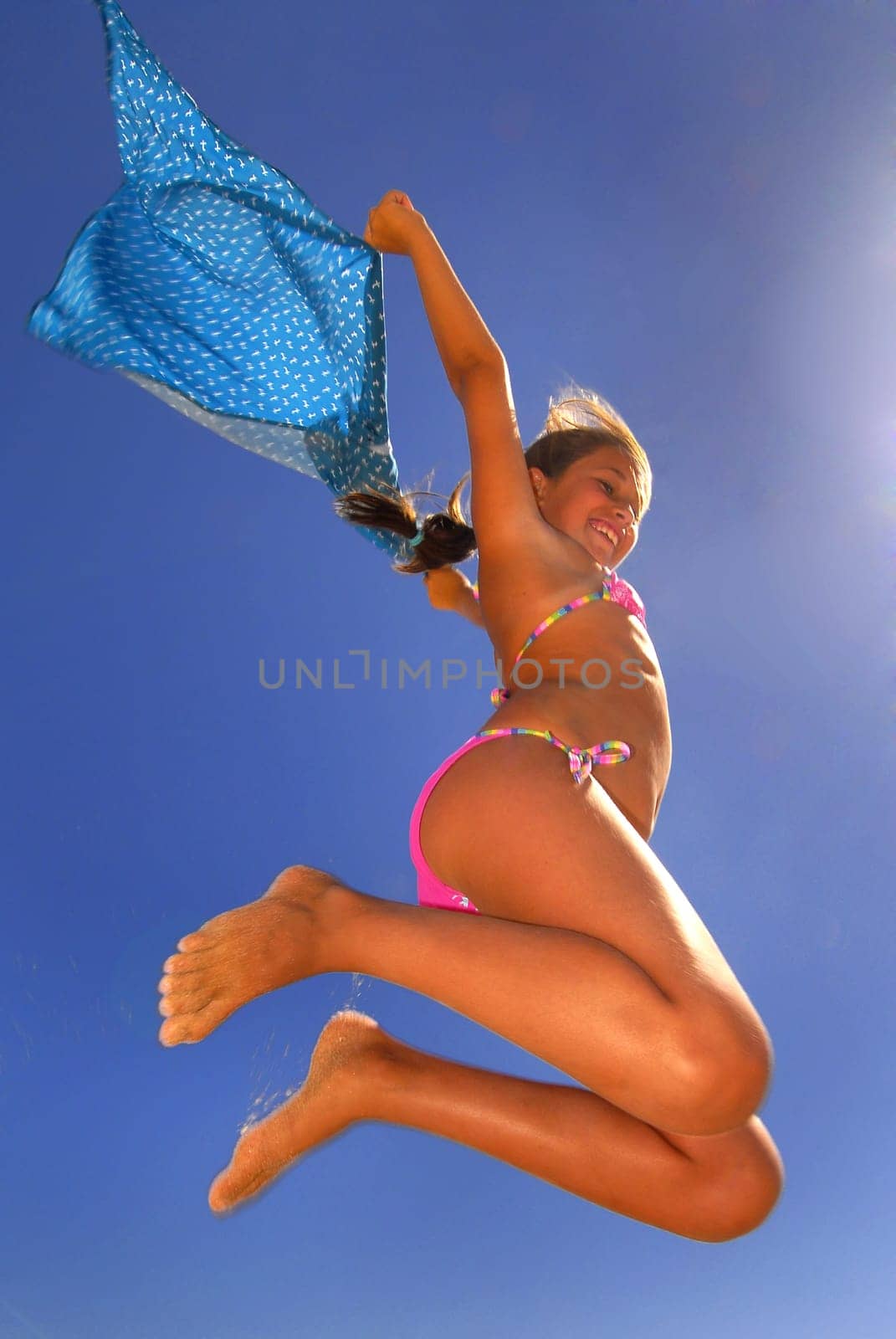 Young girl jumping in the beach with a scarf
