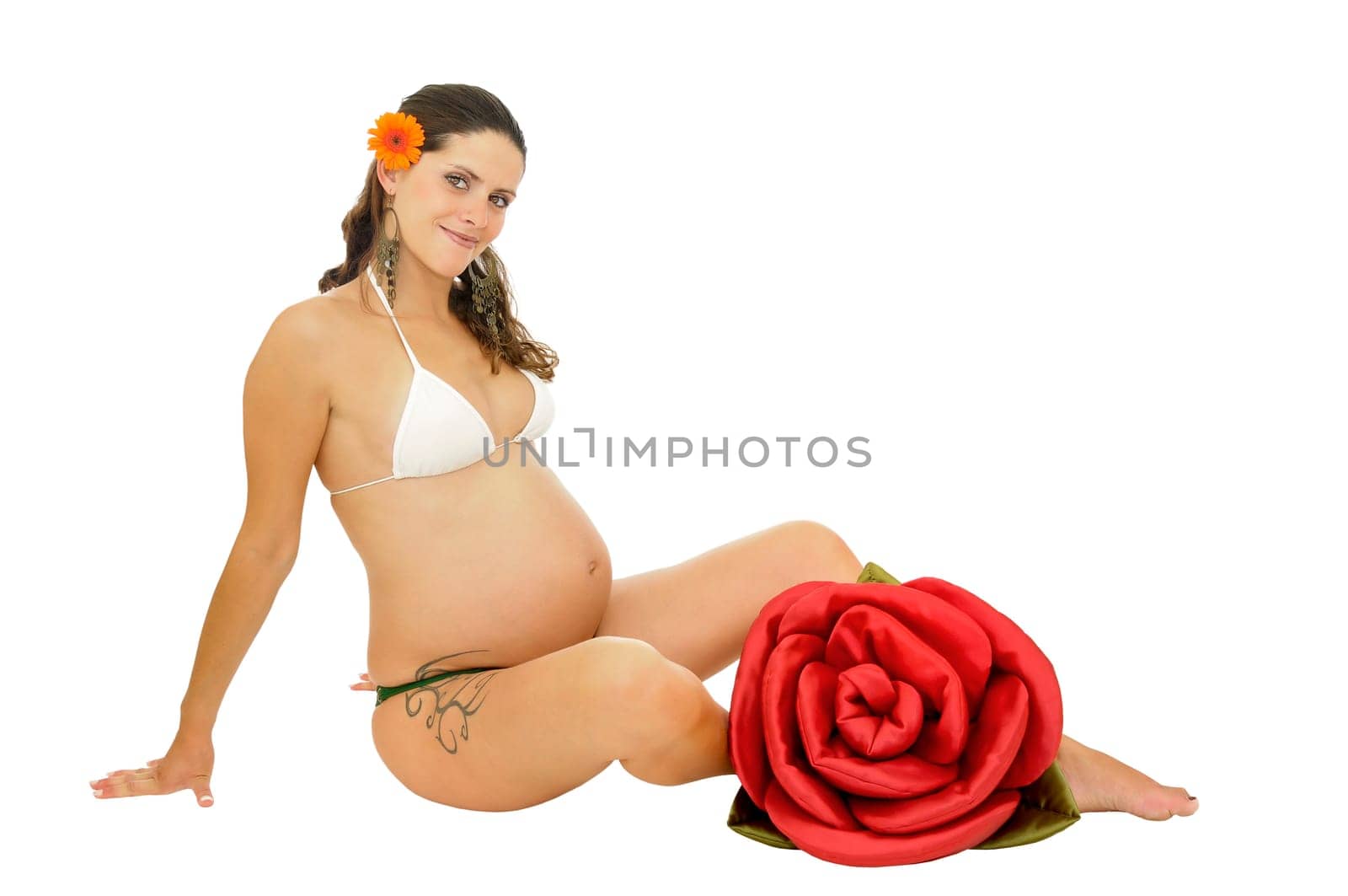Pregnant woman with tattoo posing in bikini with a red rose isolated in white