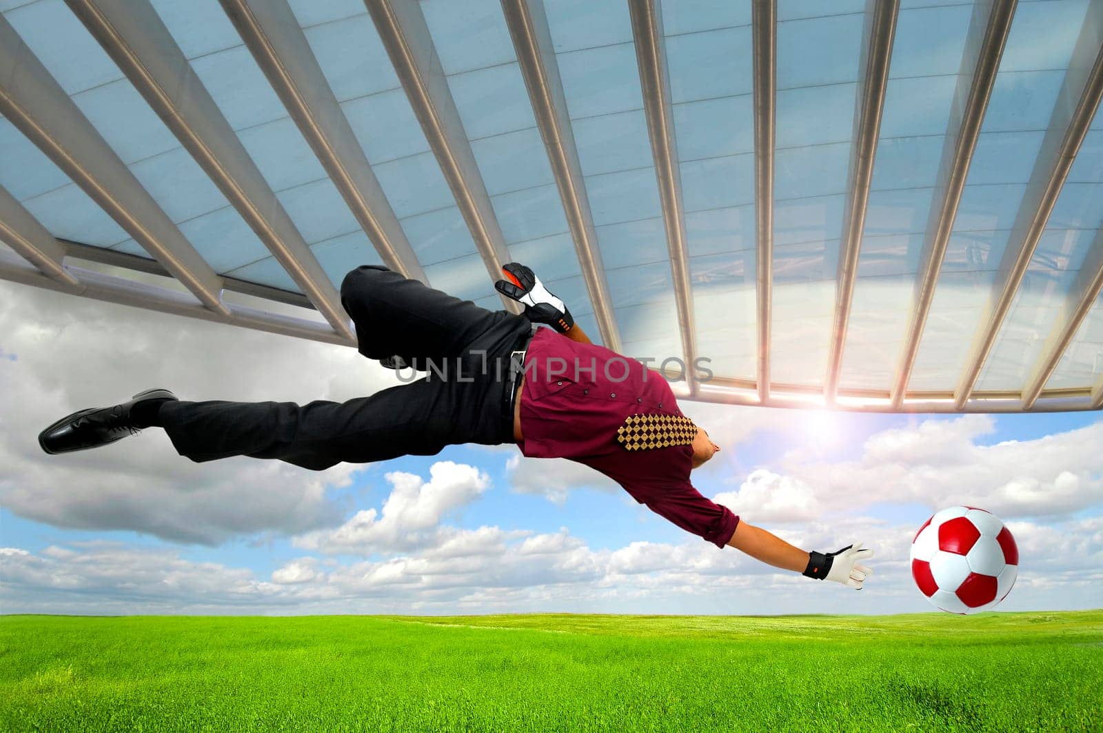 Businessman playing soccer outdoors in a green field