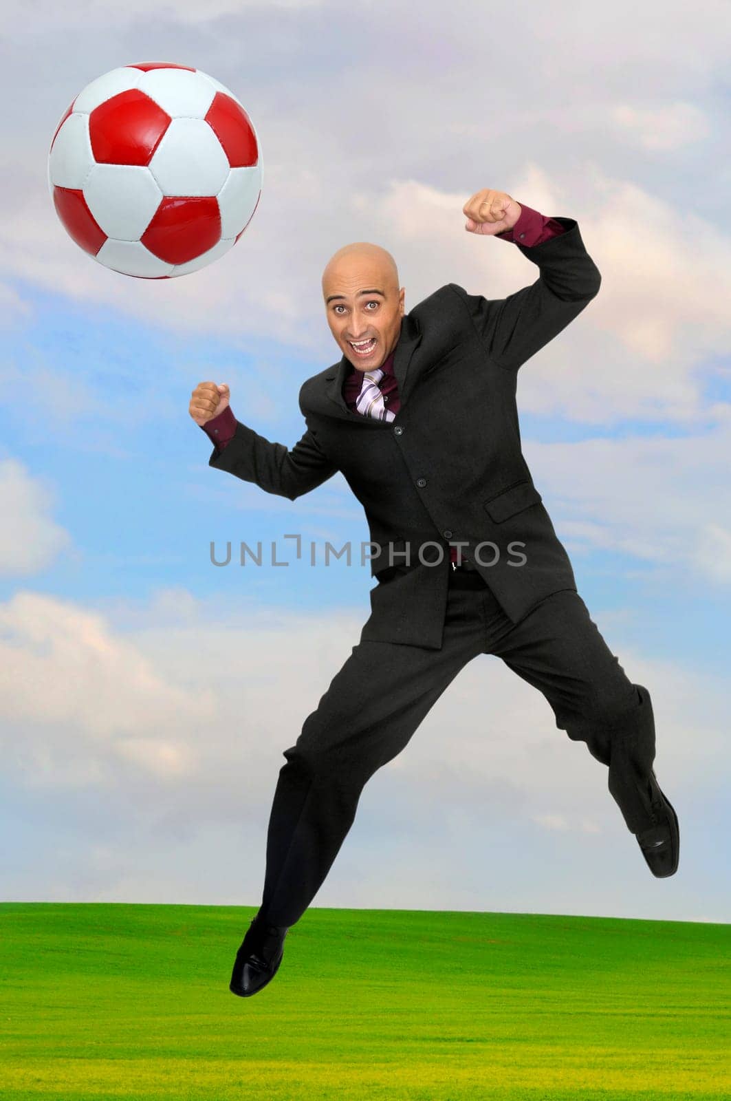 Businessman playing soccer outdoors in a green field