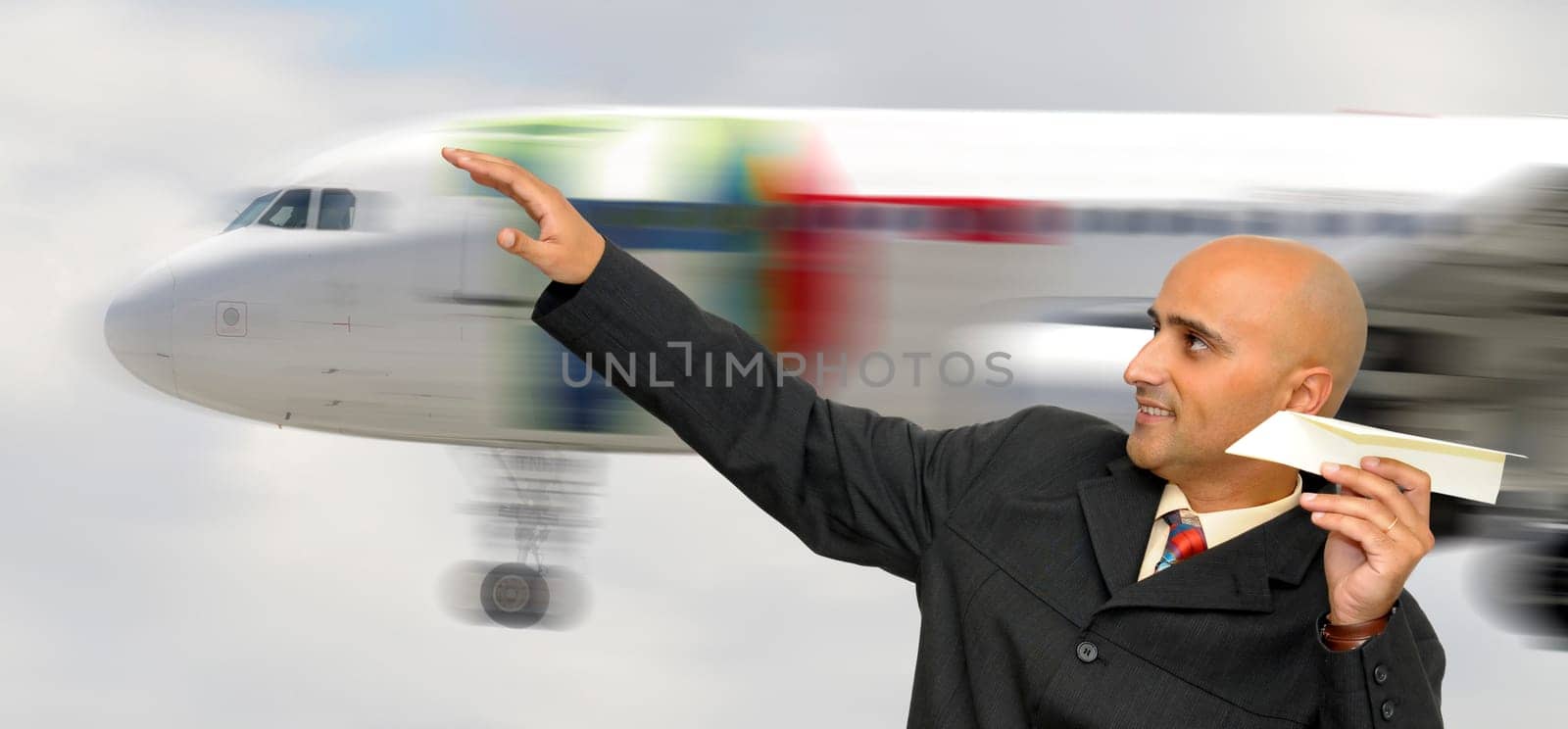 Businessman with paper plane and a jet plane passing behind
