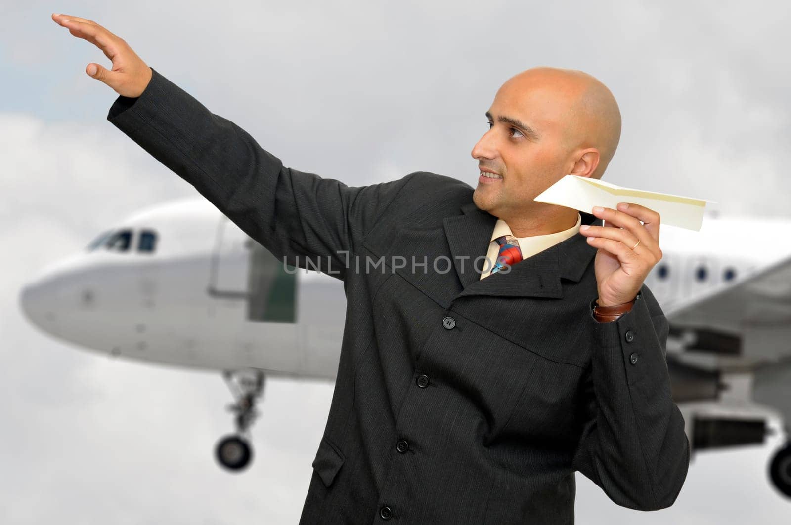Businessman with paper plane and a jet plane passing behind