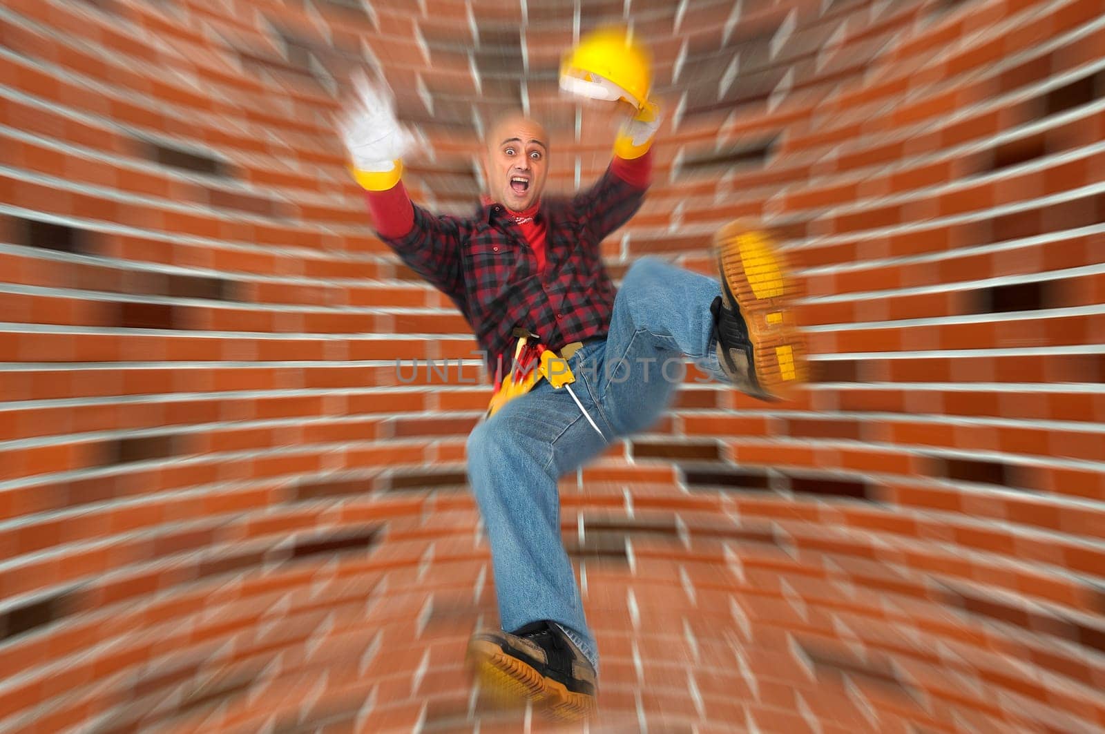 Construction worker falling with a brick wall as background