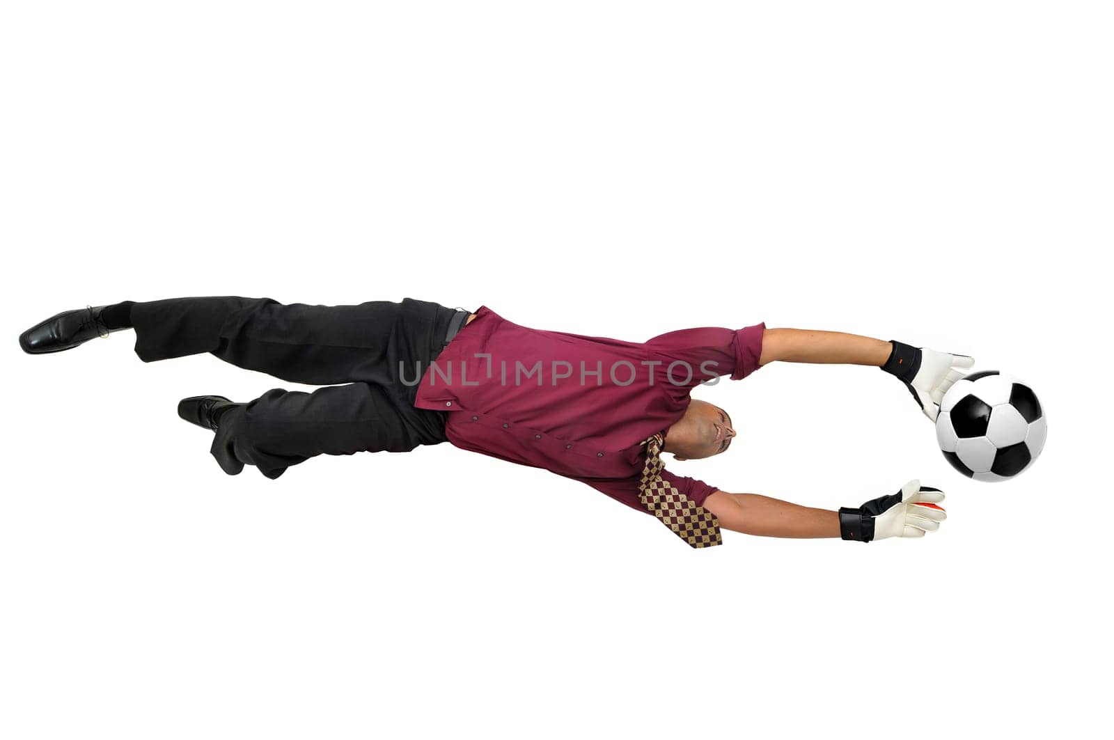 Businessman goalkeeper with gloves in a acrobatic pose with a soccer ball isolated in white
