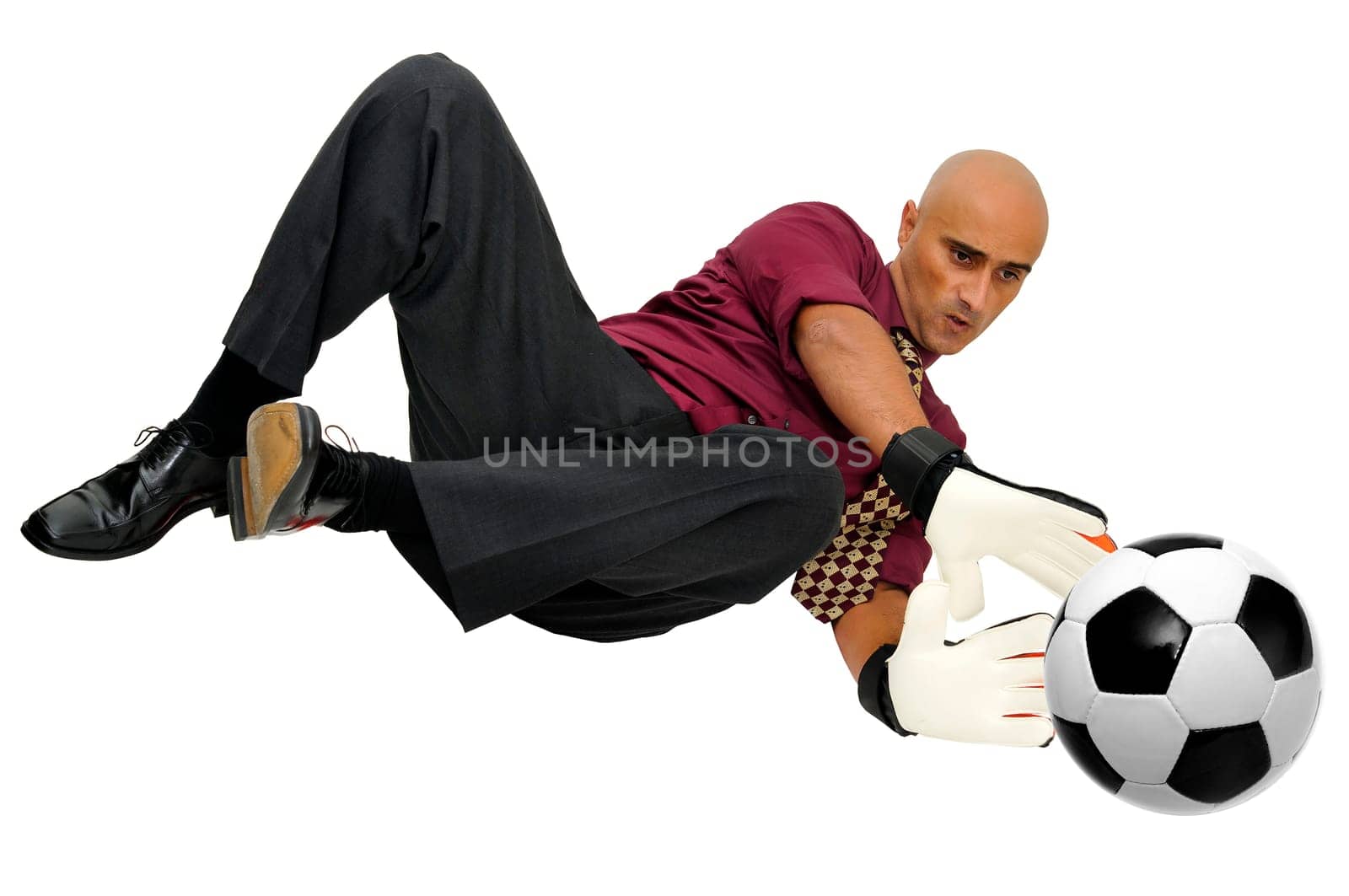 Businessman goalkeeper with gloves and ball in a acrobatic save isolated in white