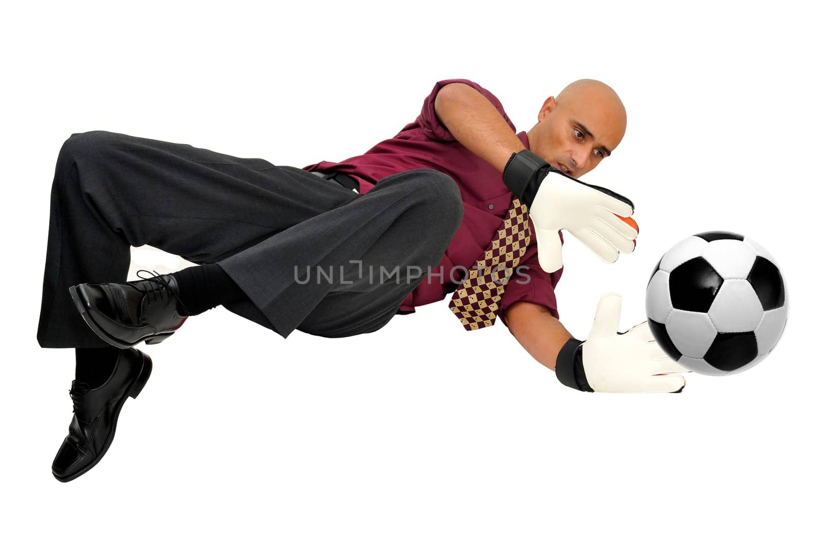 Businessman goalkeeper with gloves and ball in a acrobatic save isolated in white