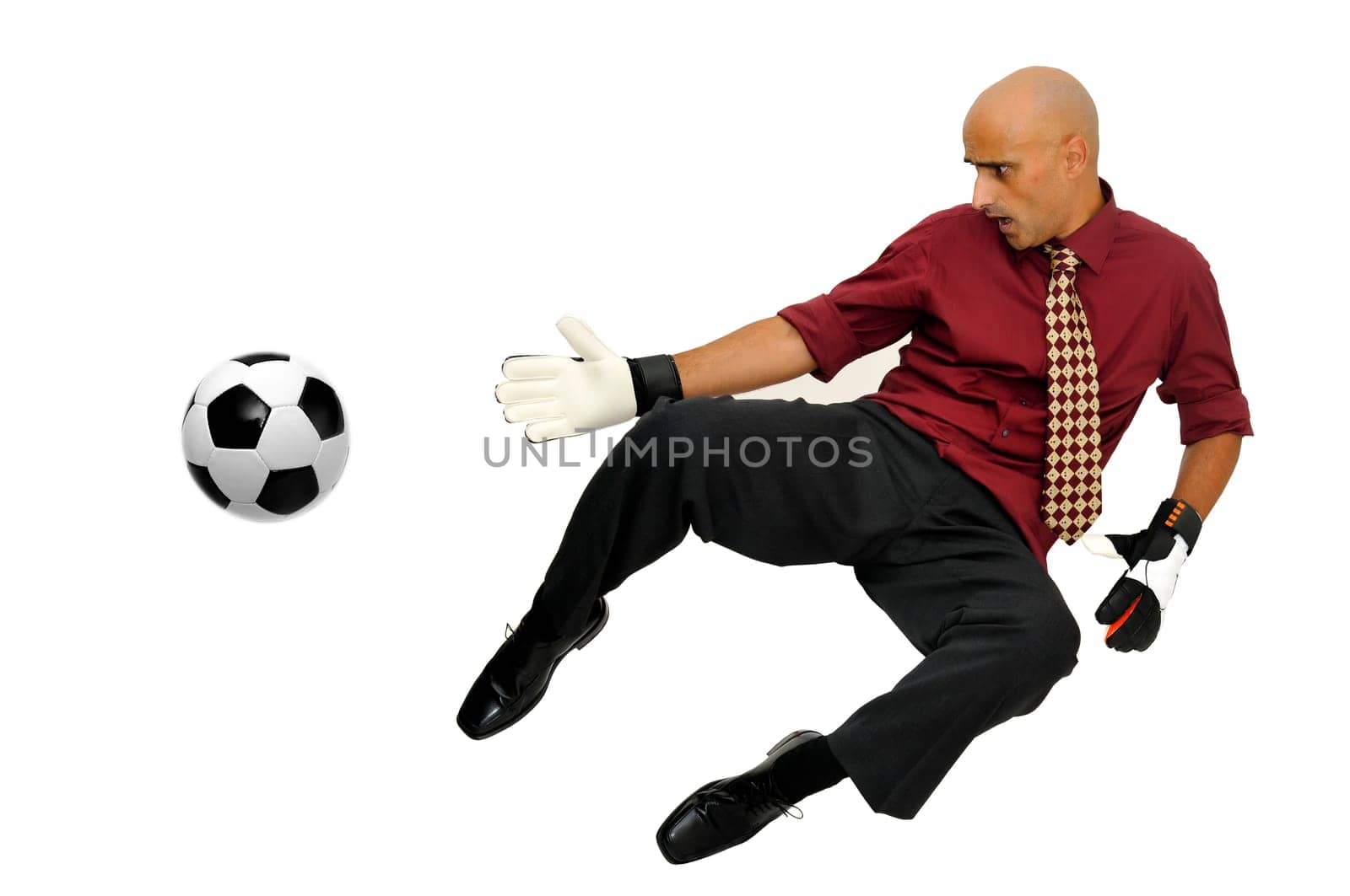 Businessman goalkeeper with gloves and ball in a acrobatic save isolated in white