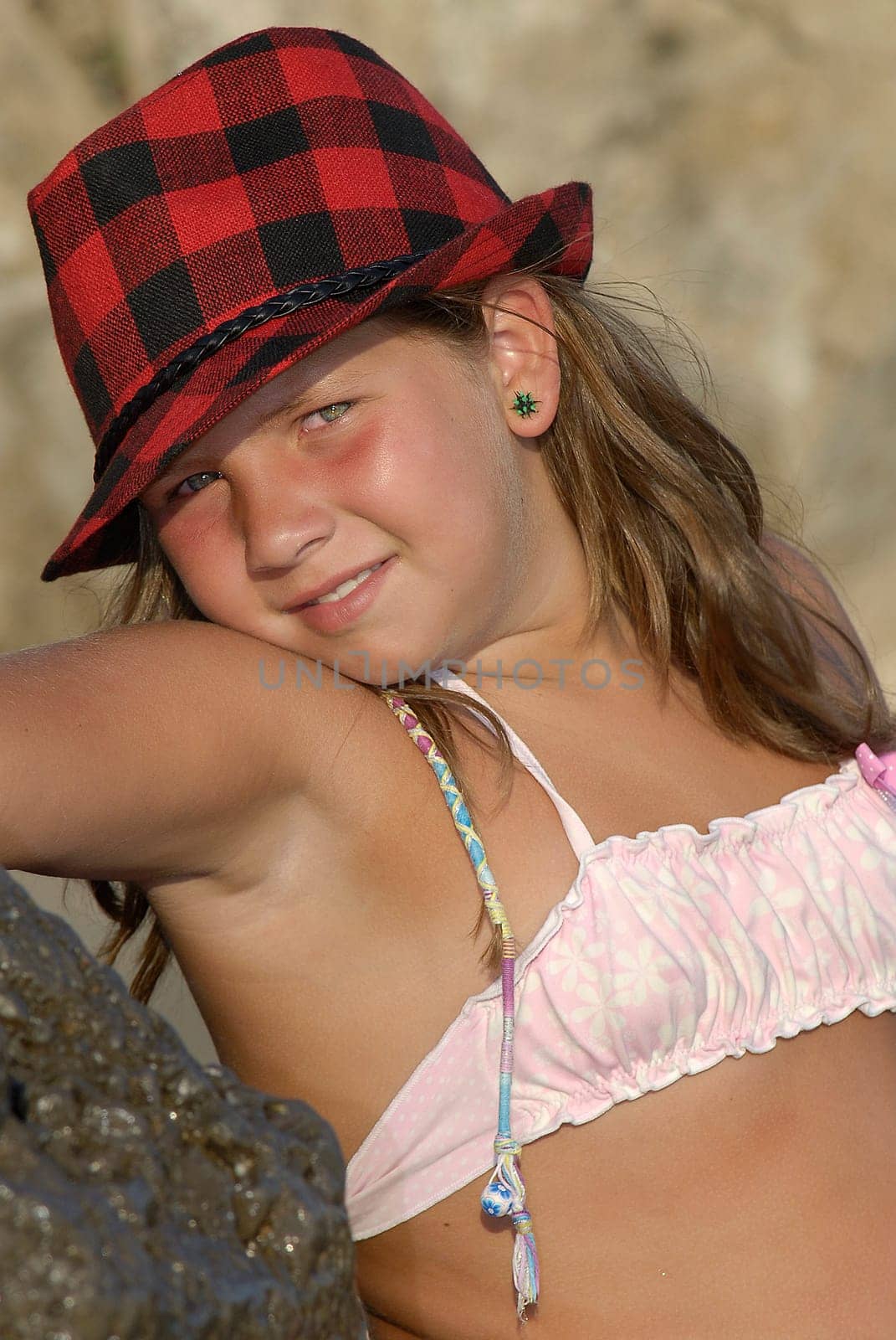 Beautiful young girl posing with hat in the beach