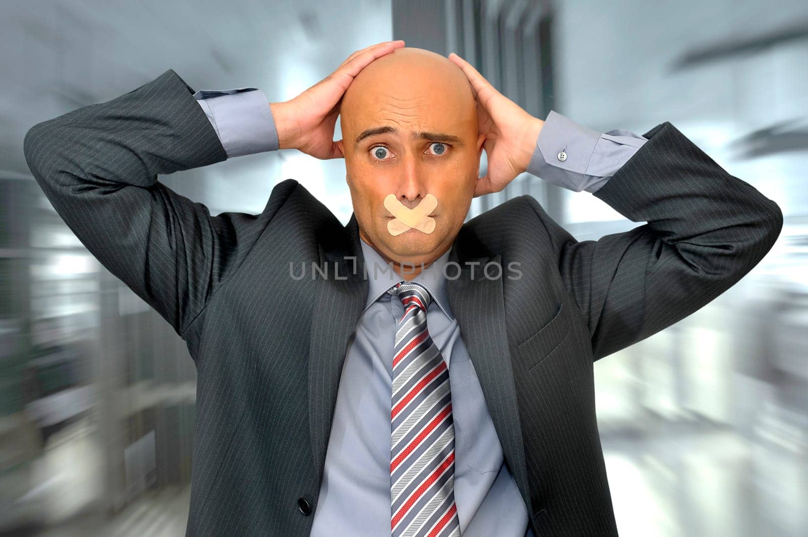 Distressed businessman with hands in his head and mouth covered with band aid