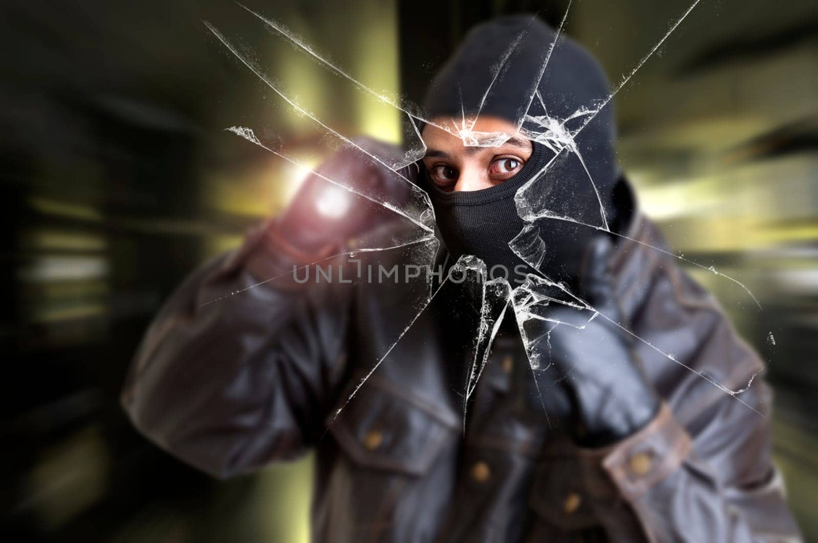 Burglar with flashlight over a broken glass