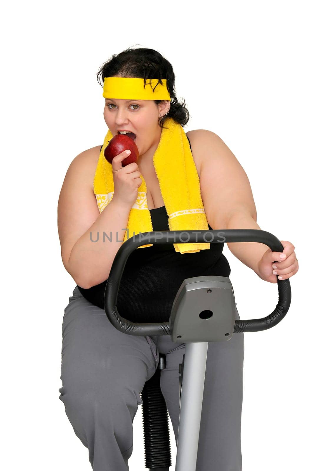 Large girl with fitness bicycle holding an apple isolated in white