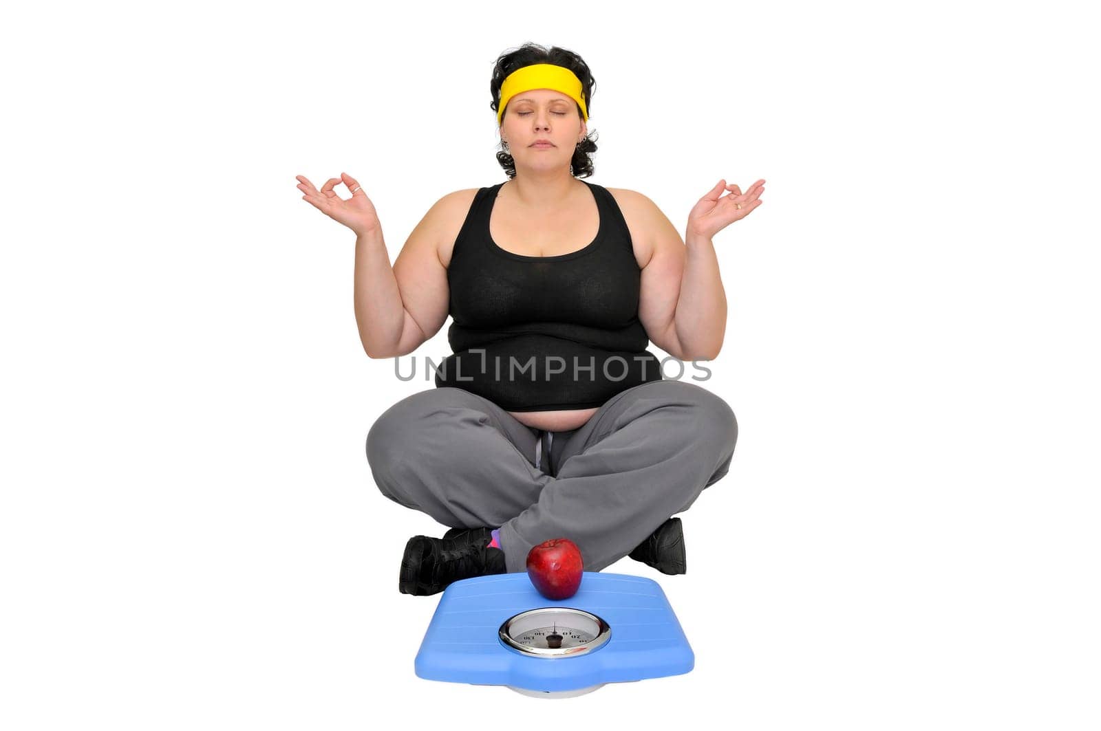 Large girl sitting near a scale with an apple doing yoga exercises