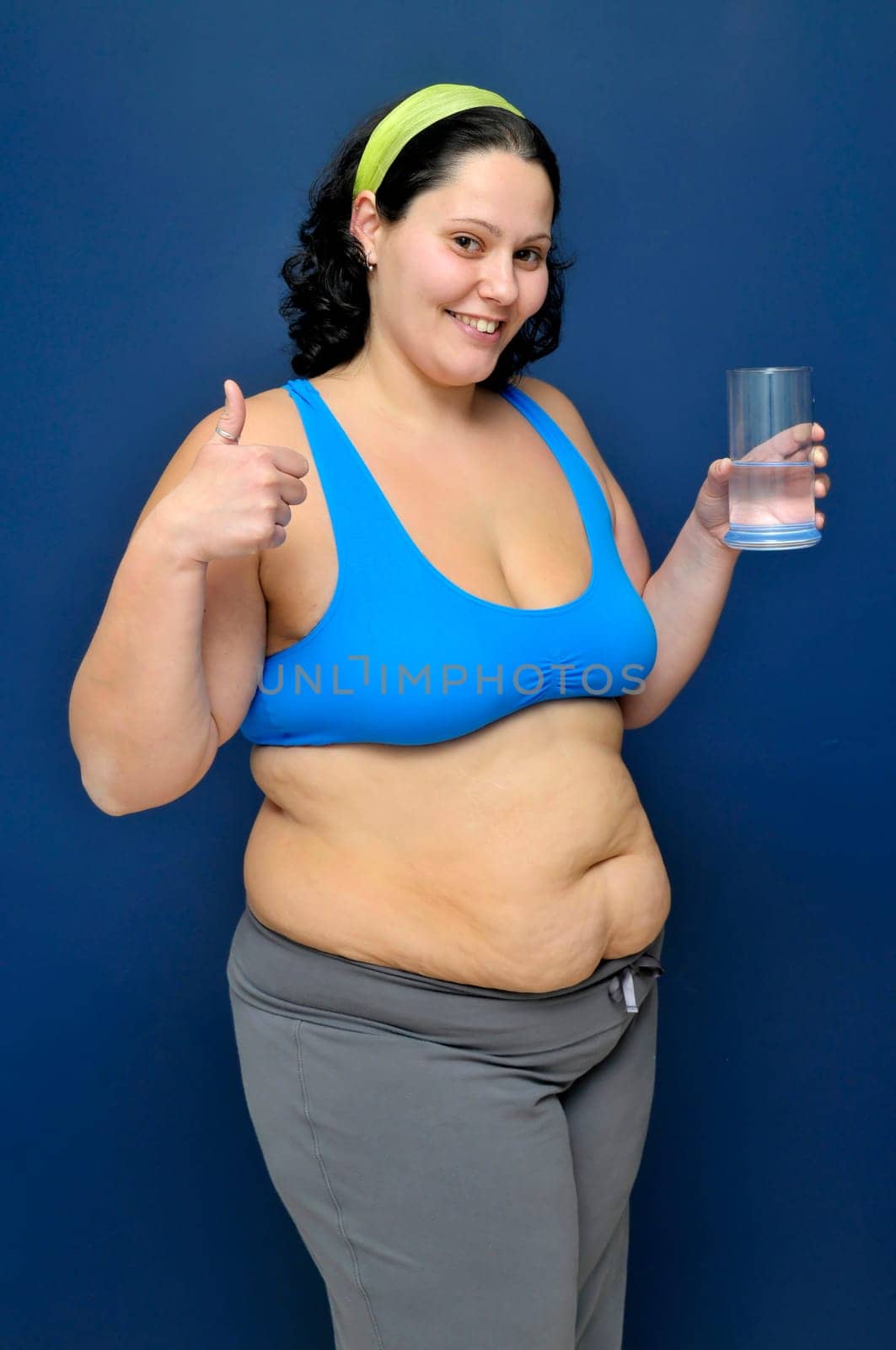 Large girl in fitness outfit with a glass of water