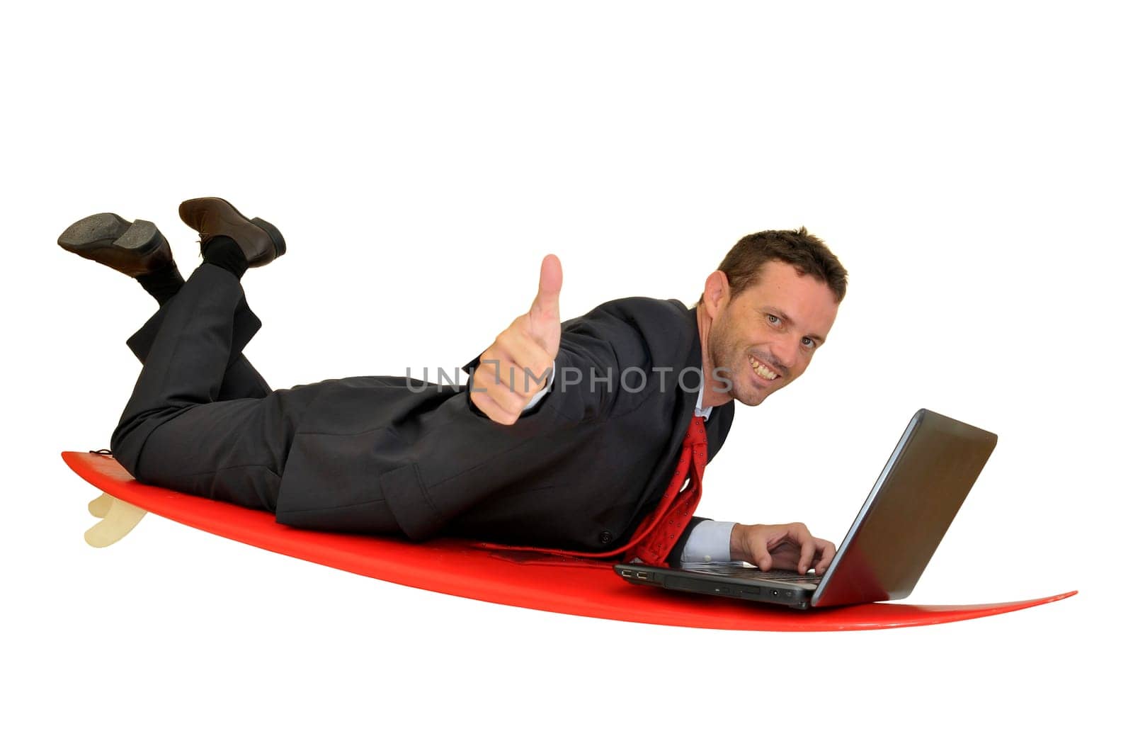 Young businessman laying in a surf board with laptop