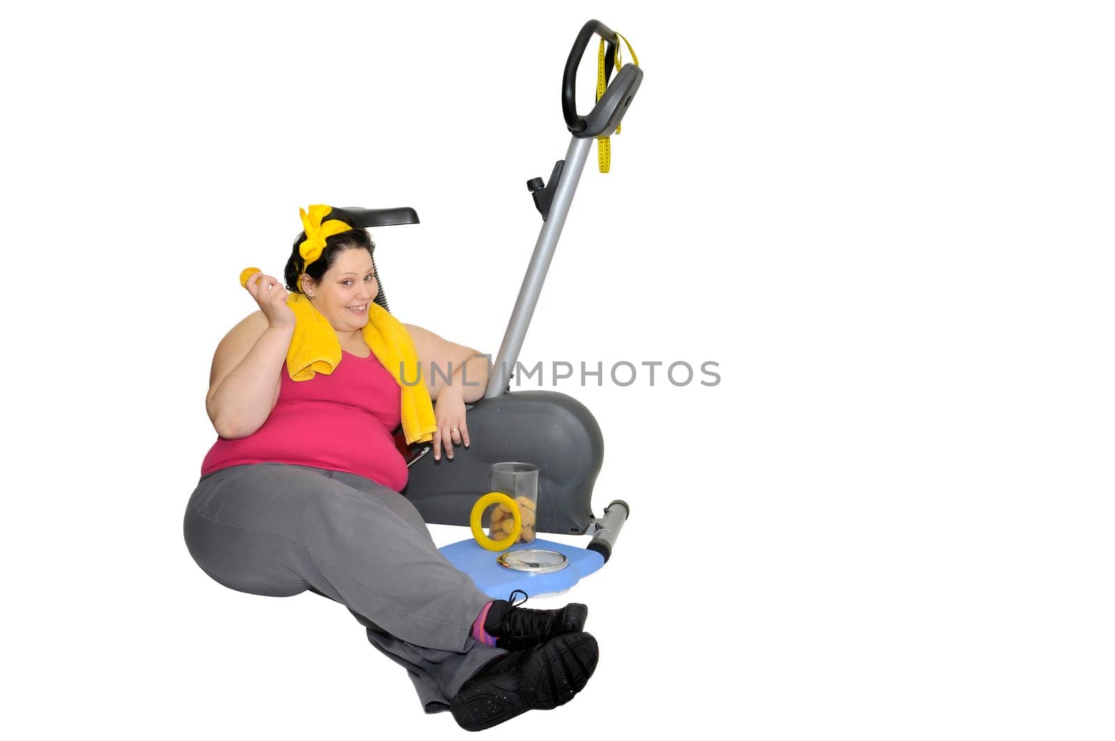 Large girl laying near a fitness bicycle eating cookies