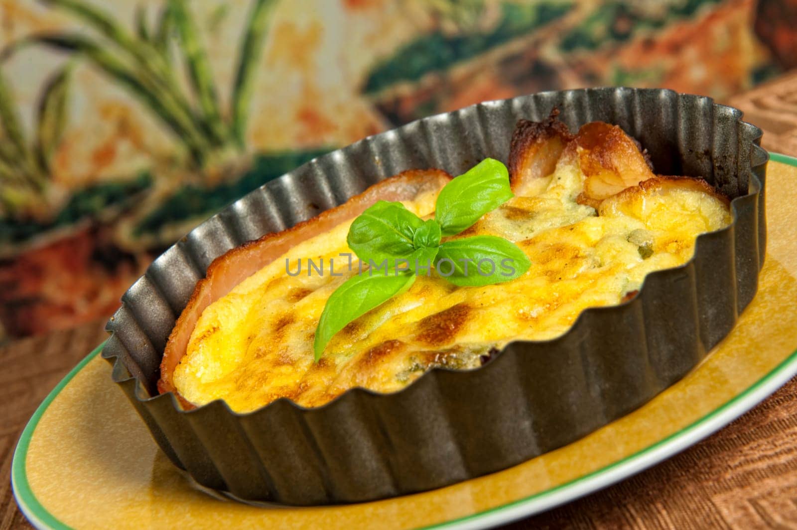 Eggs and bacon tart with basil leaves